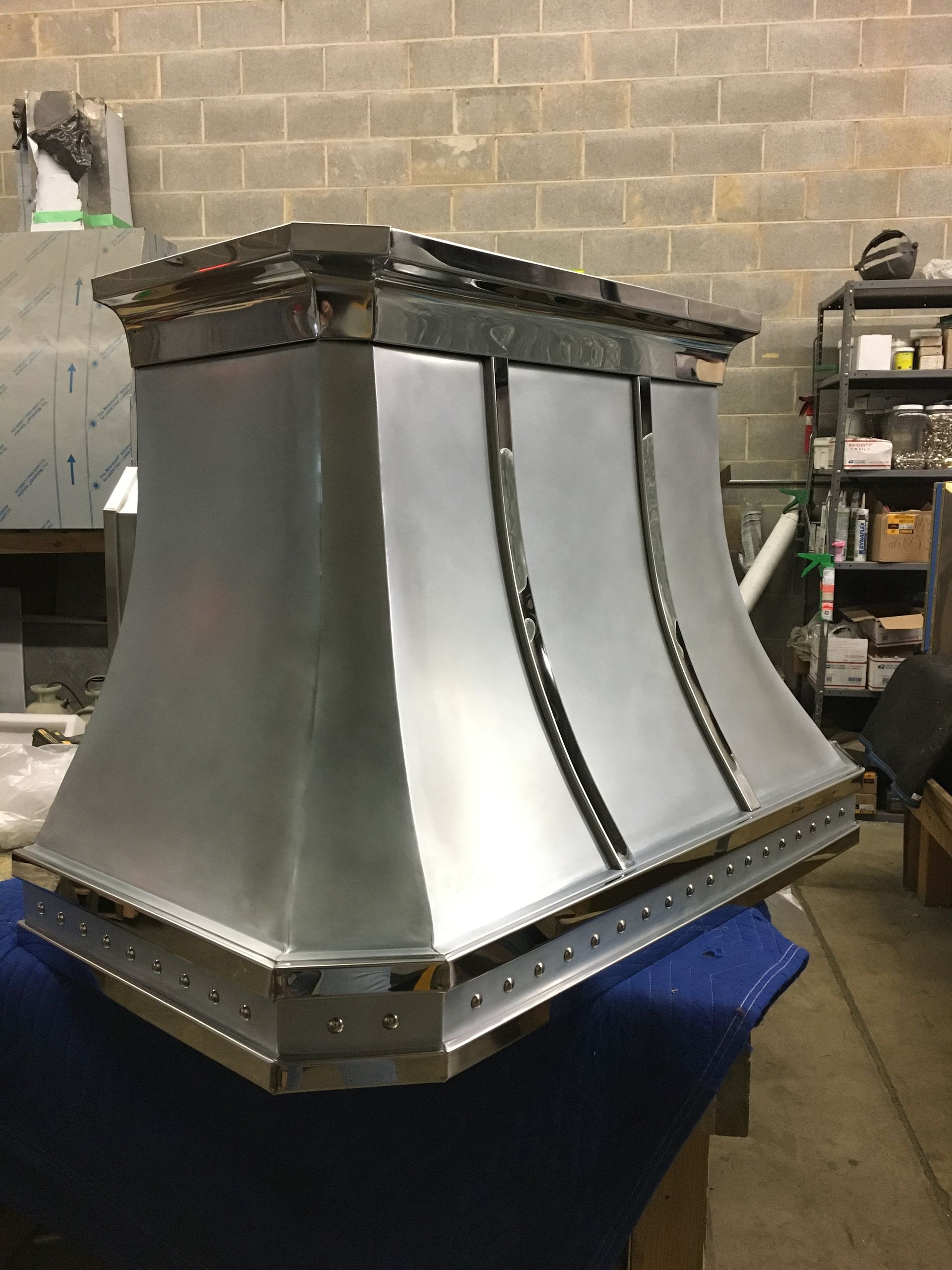 Metal industrial duct or vent housing with curved silver panels in a workshop setting