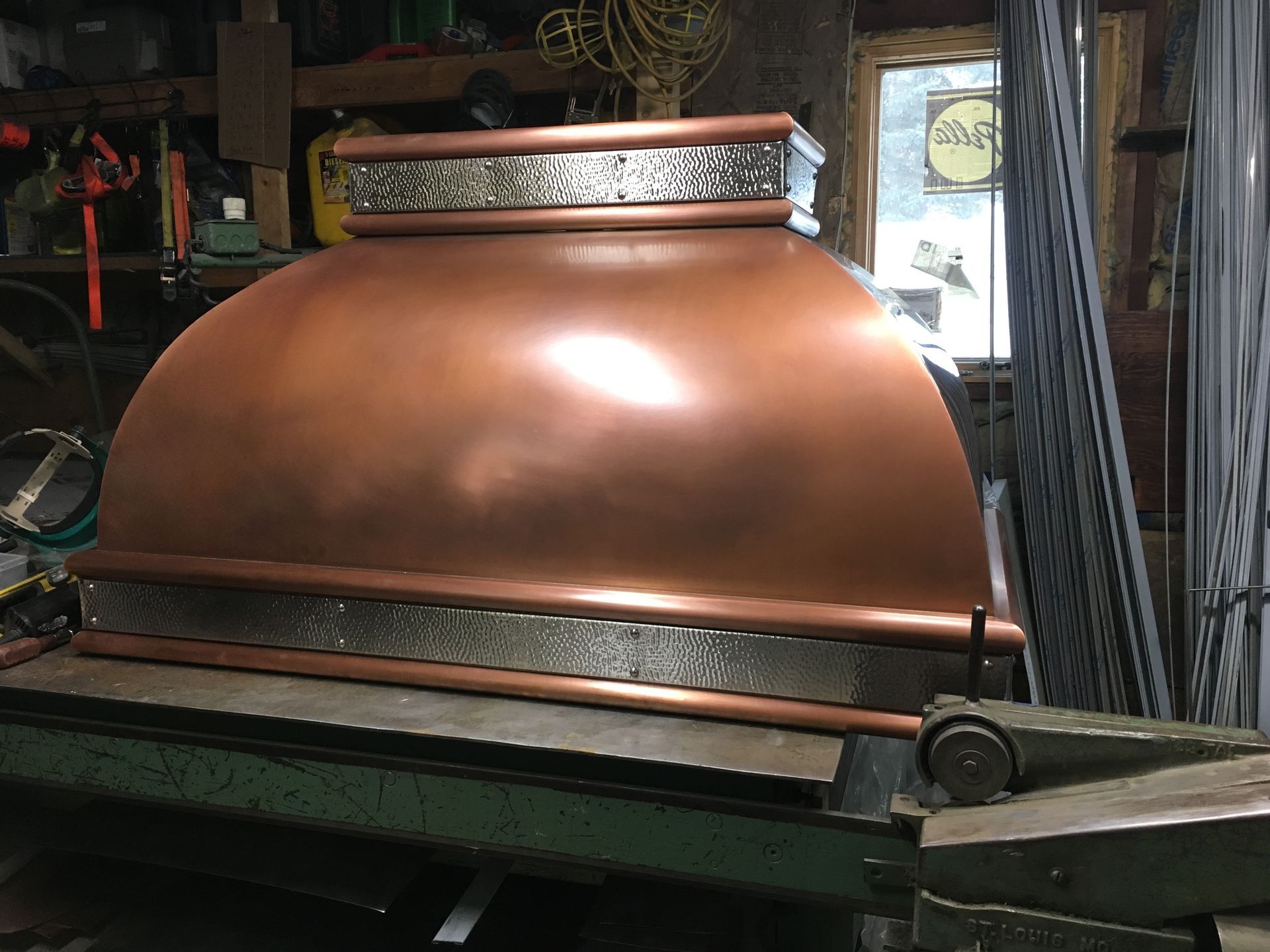 Copper brewing kettle with a domed lid in a rustic workshop