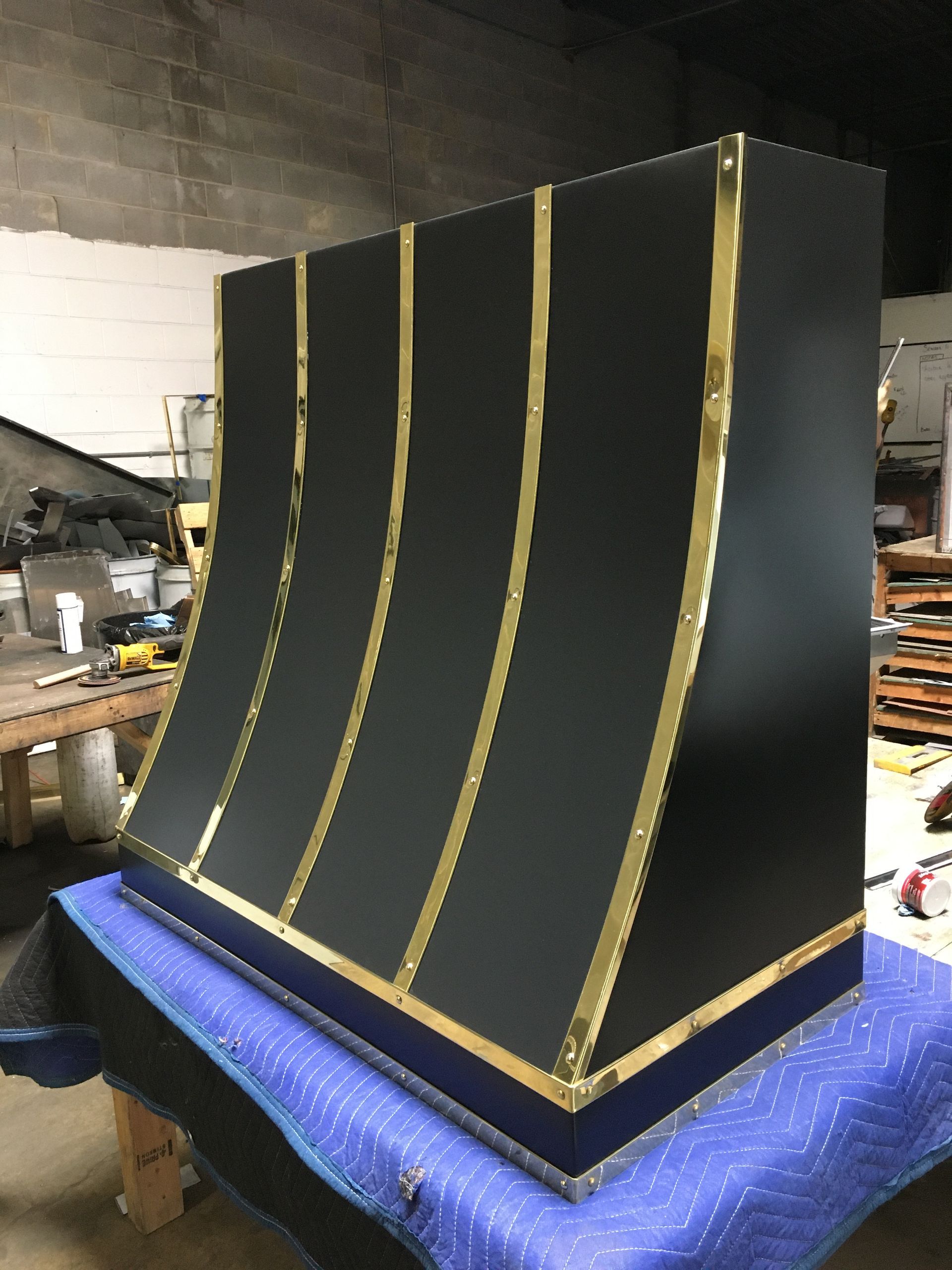 Large black panel with gold vertical stripes, leaning on a workbench in a cluttered workshop