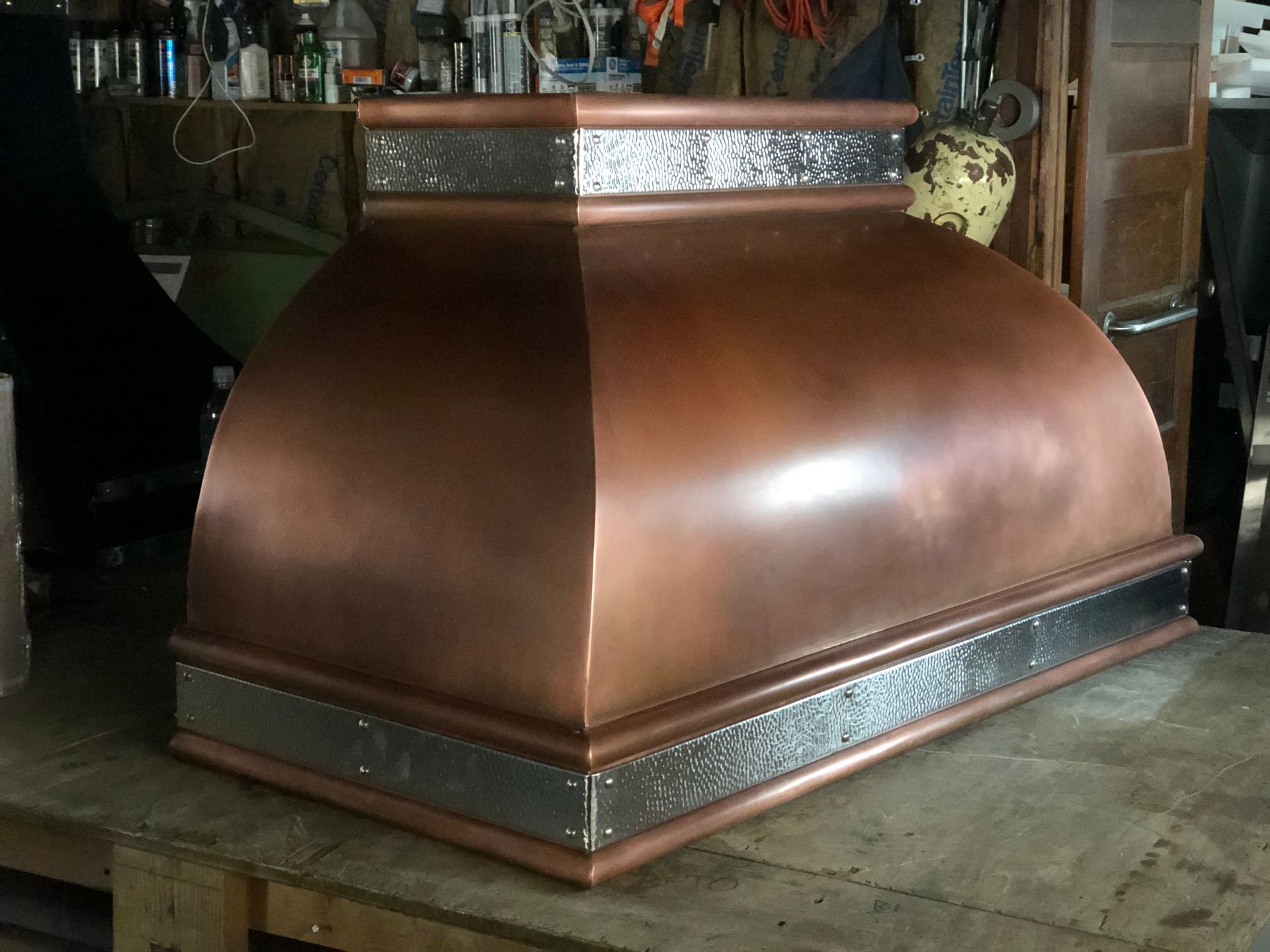 Copper range hood with decorative trim in a rustic kitchen