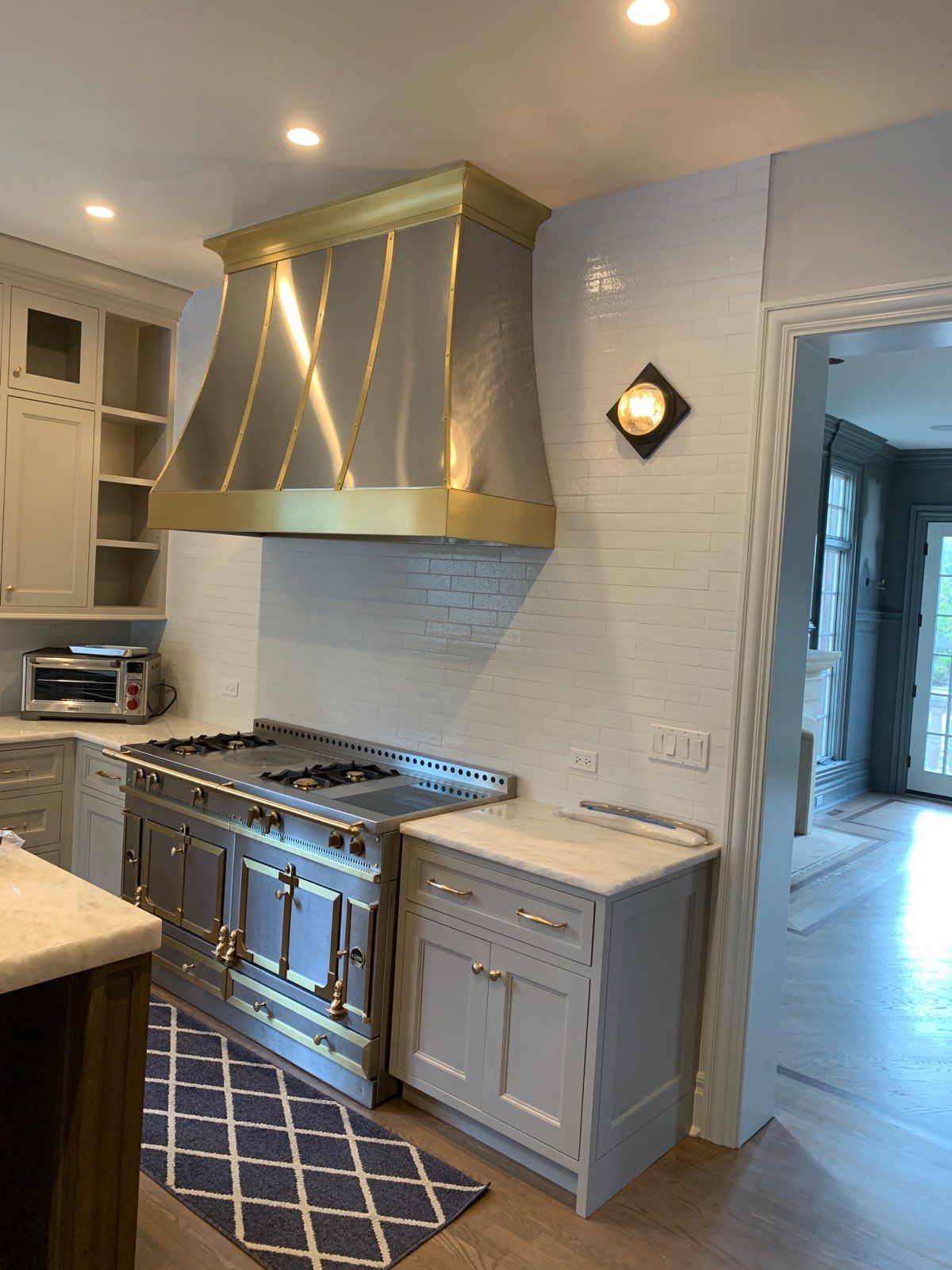 Modern kitchen with blue cabinetry, gold range hood, stainless stove, and white countertops