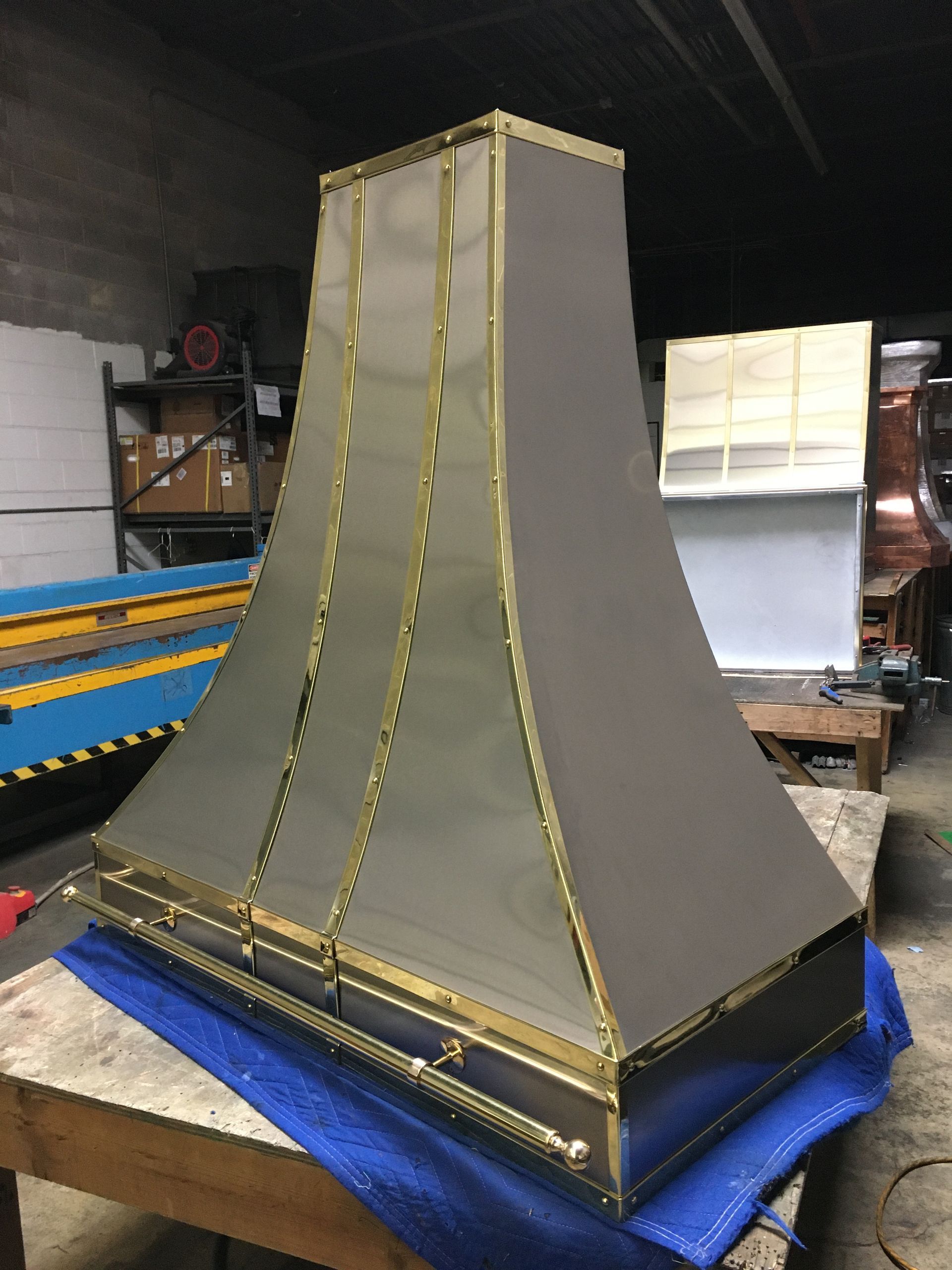 Gray tapered model with gold trim on a blue base in a workshop environment