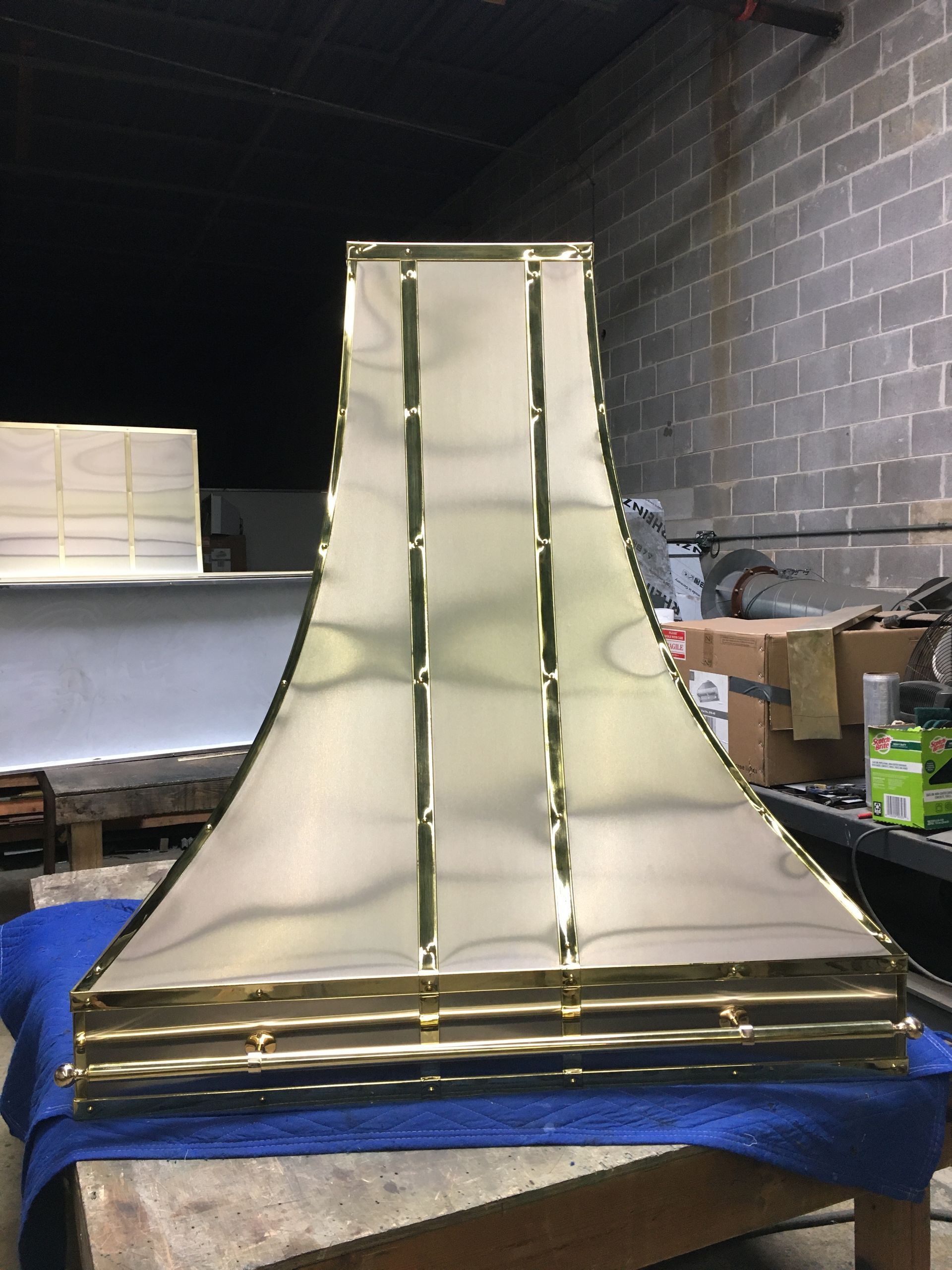 Large white curved ramp or chute with gold trim on a blue tarp in a dim workshop garage