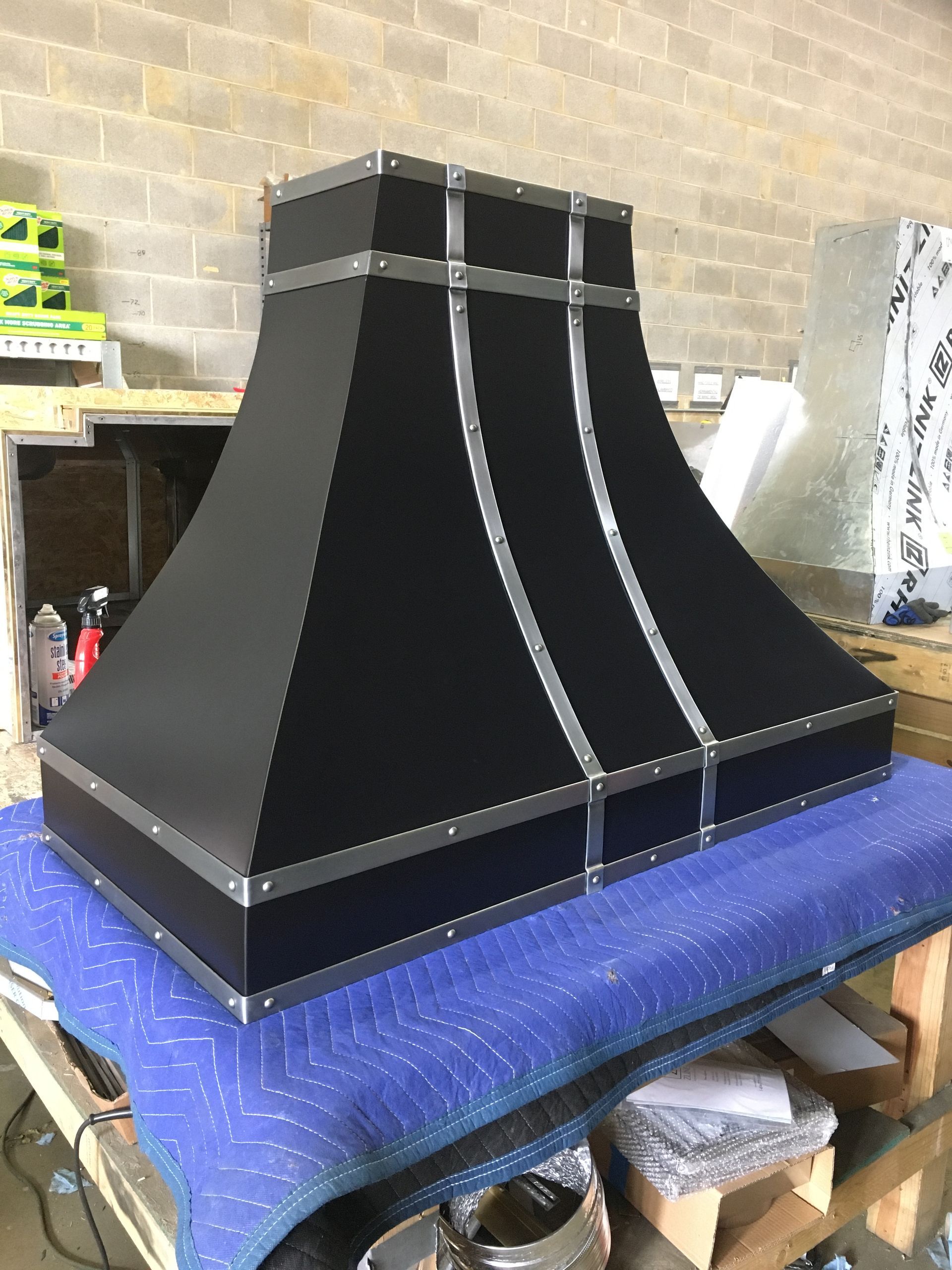 Black tapered wooden structure with silver trim on a worktable in a workshop