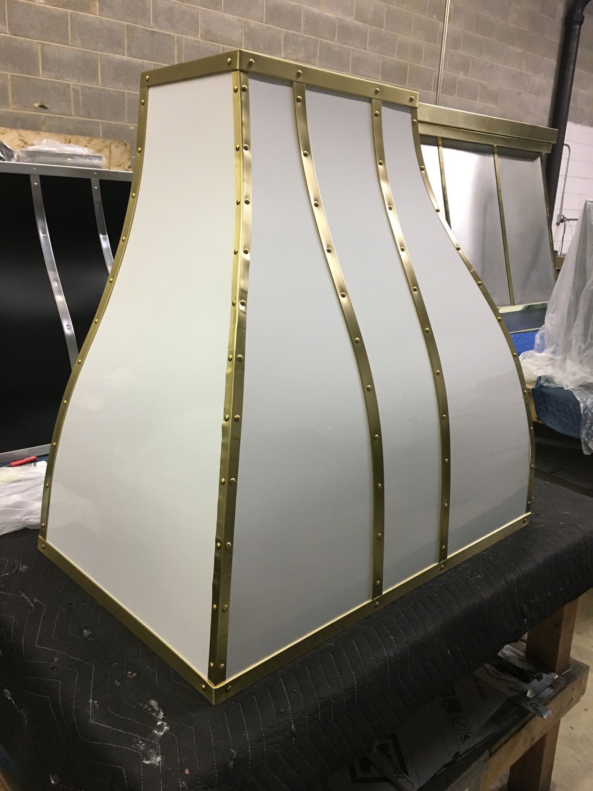 White, gold-trimmed lantern-style lampshade on a black worktable in a workshop