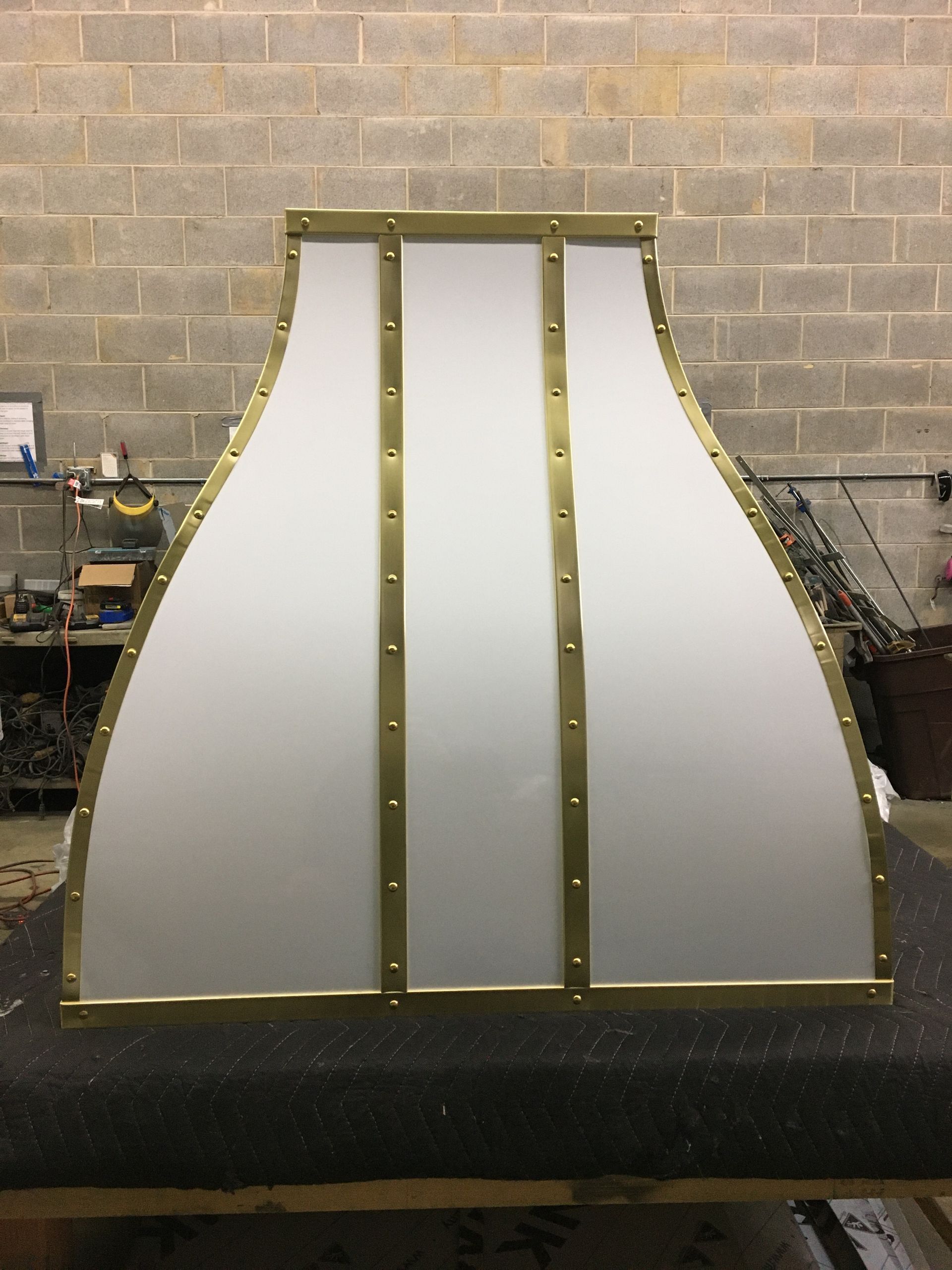 White panel structure with brass trim against a cinder block wall