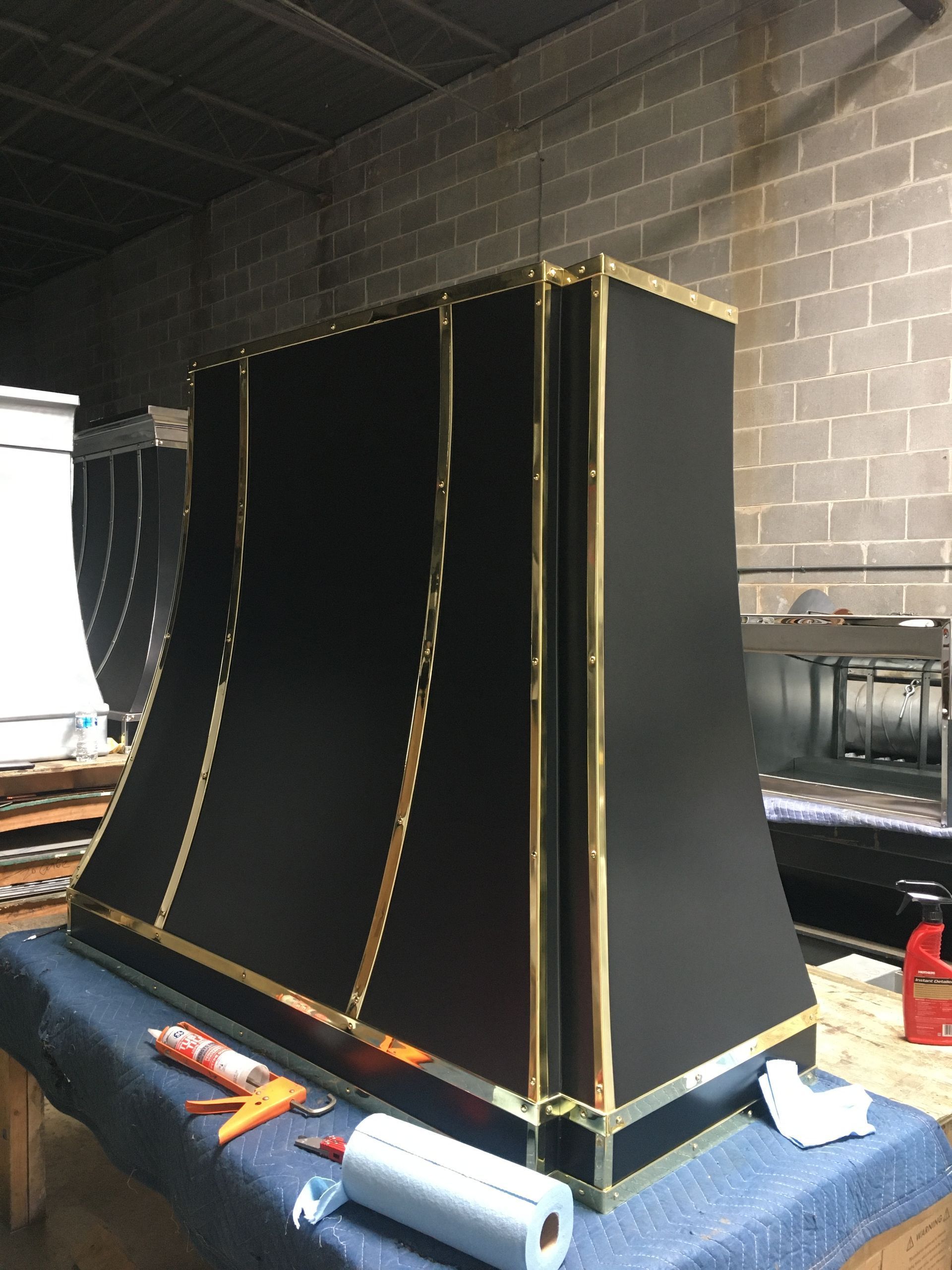 Large black box-like structure with gold trim on a workbench in a garage or workshop
