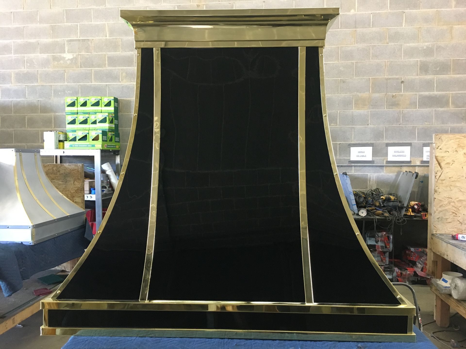 Large black and gold curved ramp or halfpipe in an indoor workshop with equipment around it