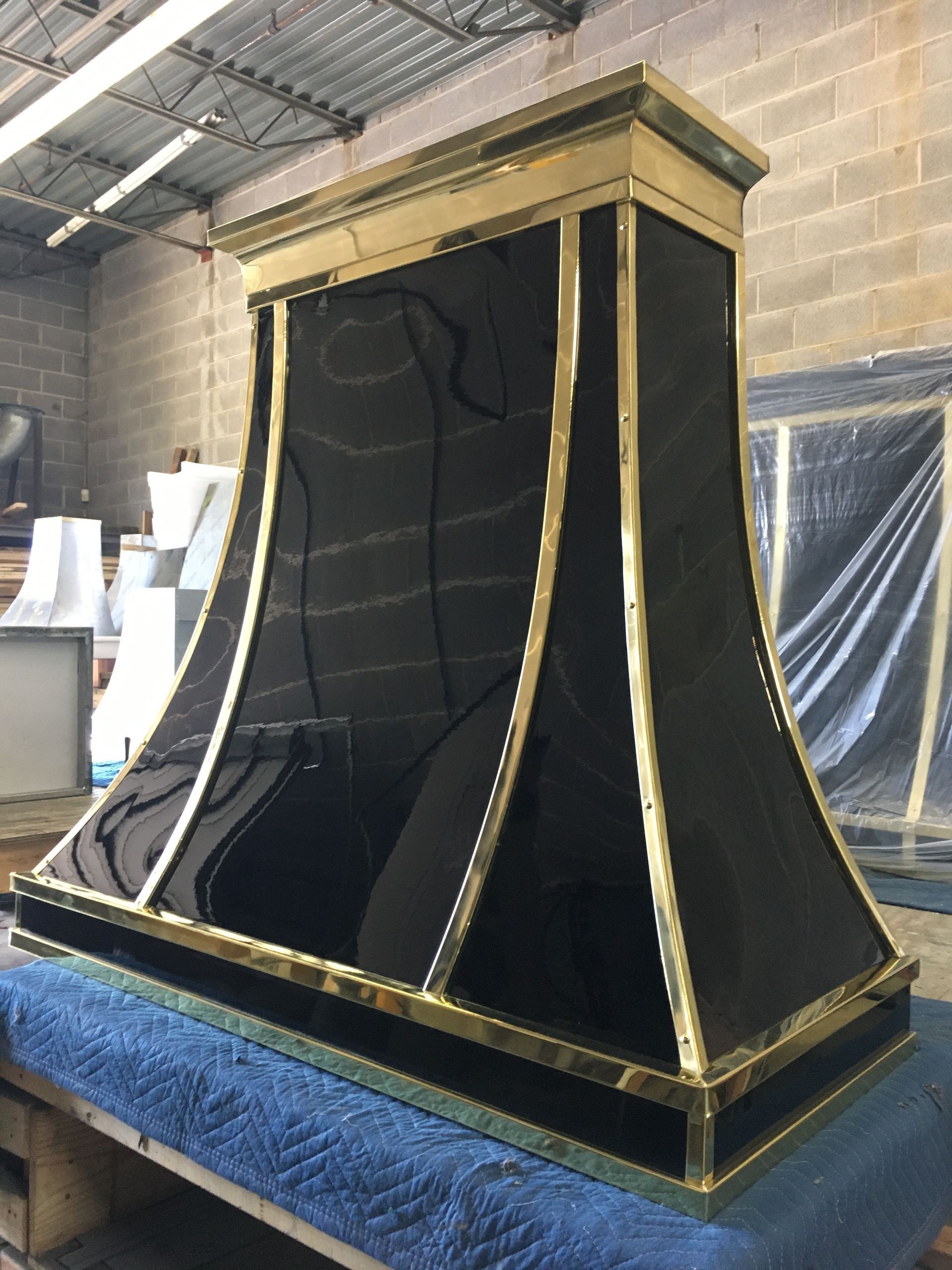 Black-and-gold decorative display booth with draped sides in a warehouse setting
