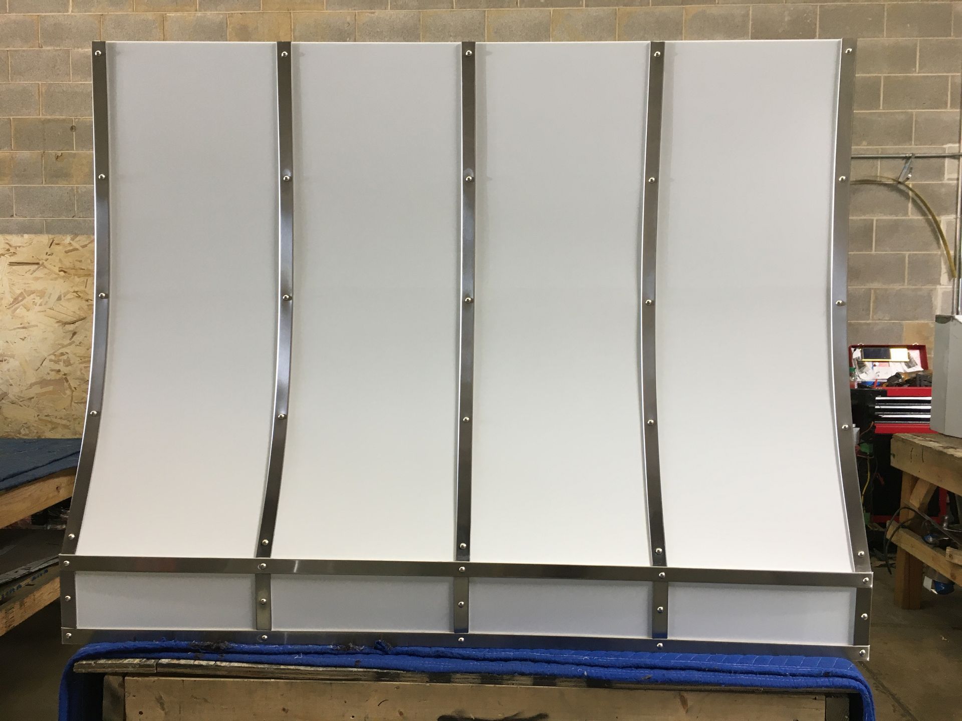 Four white curved panels mounted on a metal frame in a workshop setting