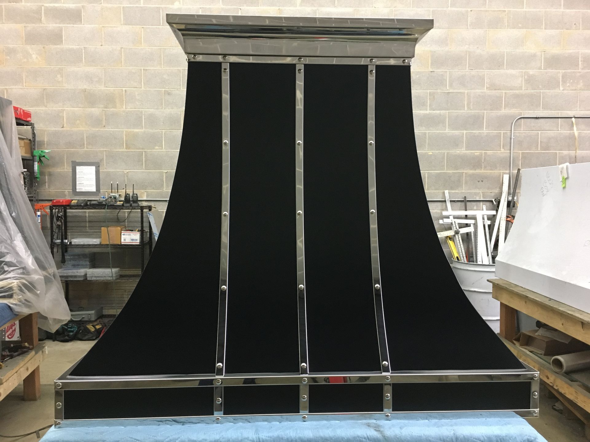 Large black curved ramp structure in a workshop, with a platform and metal supports