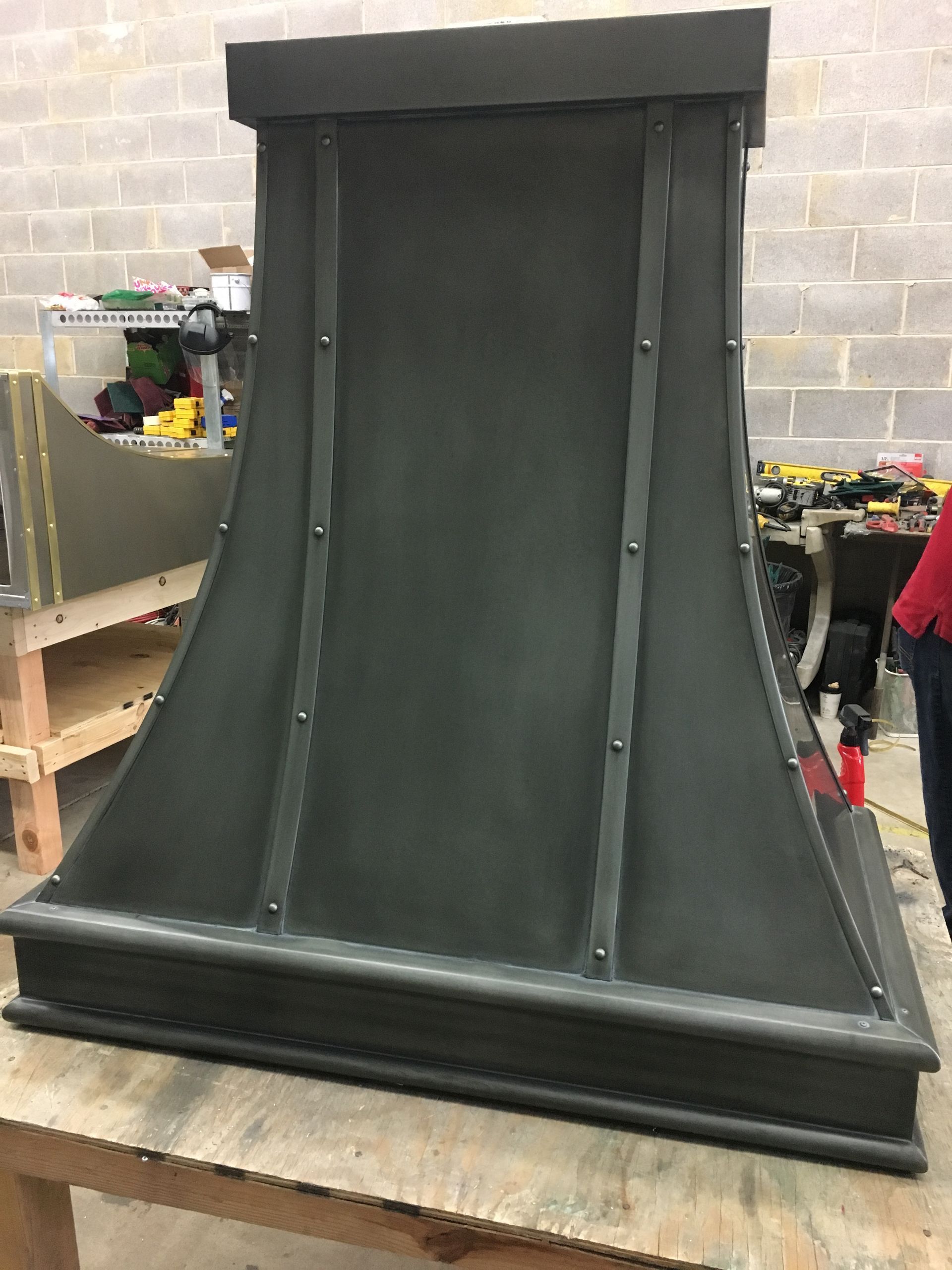 Large black curved metal panel on a workshop table with a broad base and top frame