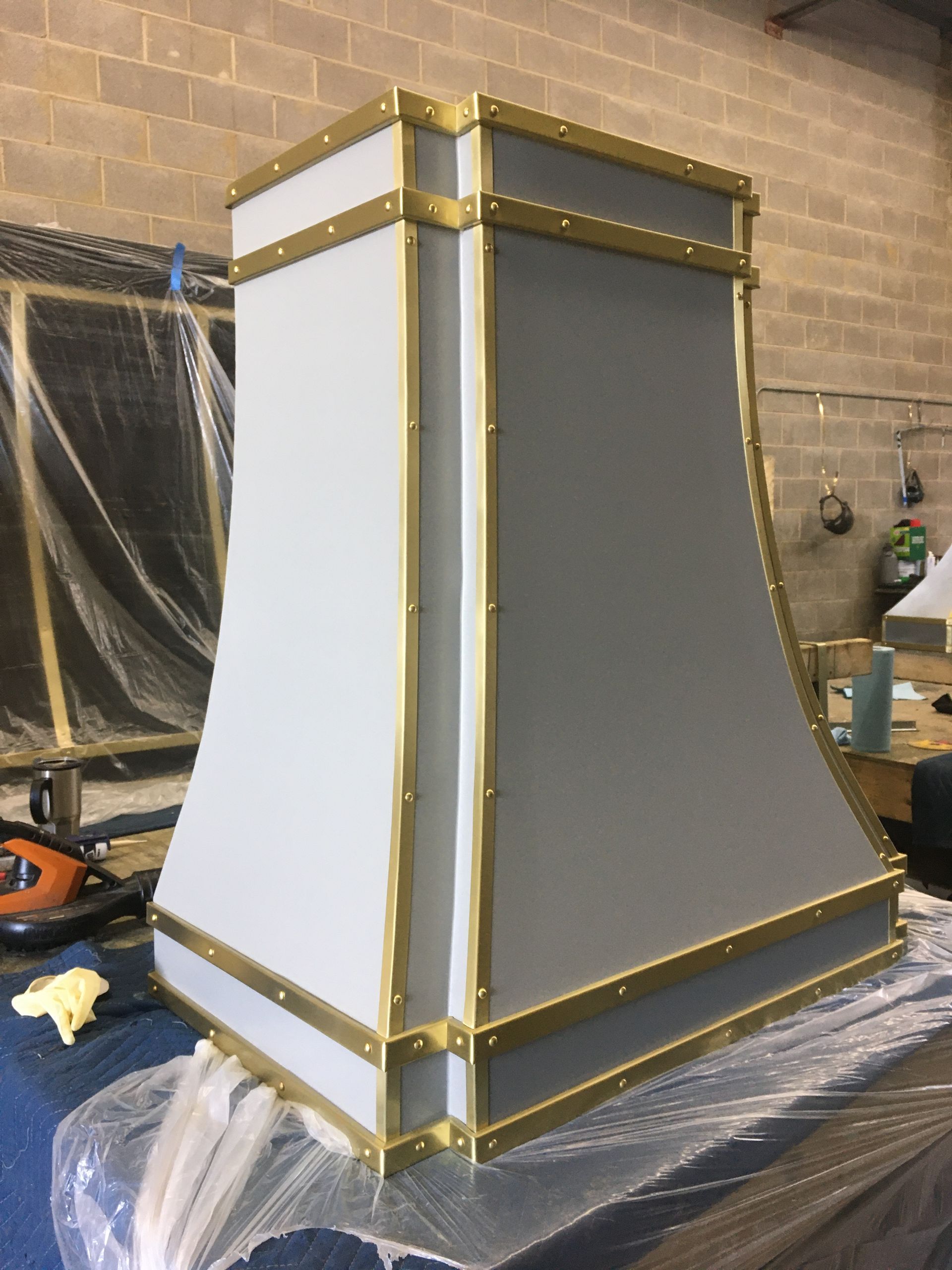 Gray and gold decorative column structure in a workshop, wrapped in plastic on a worktable
