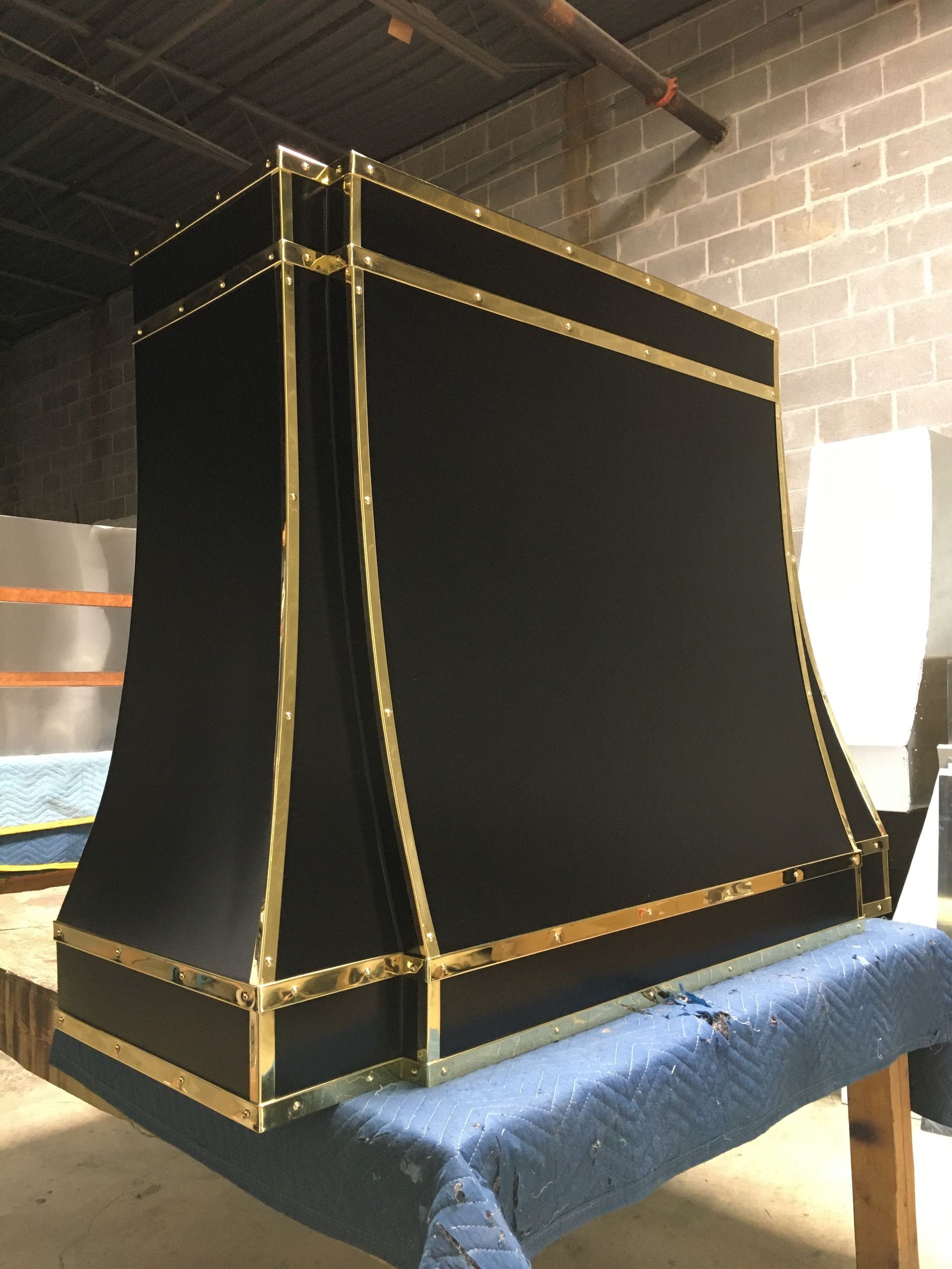 Black and gold striped fabric-covered box or prop on a blue table in a brick-walled room