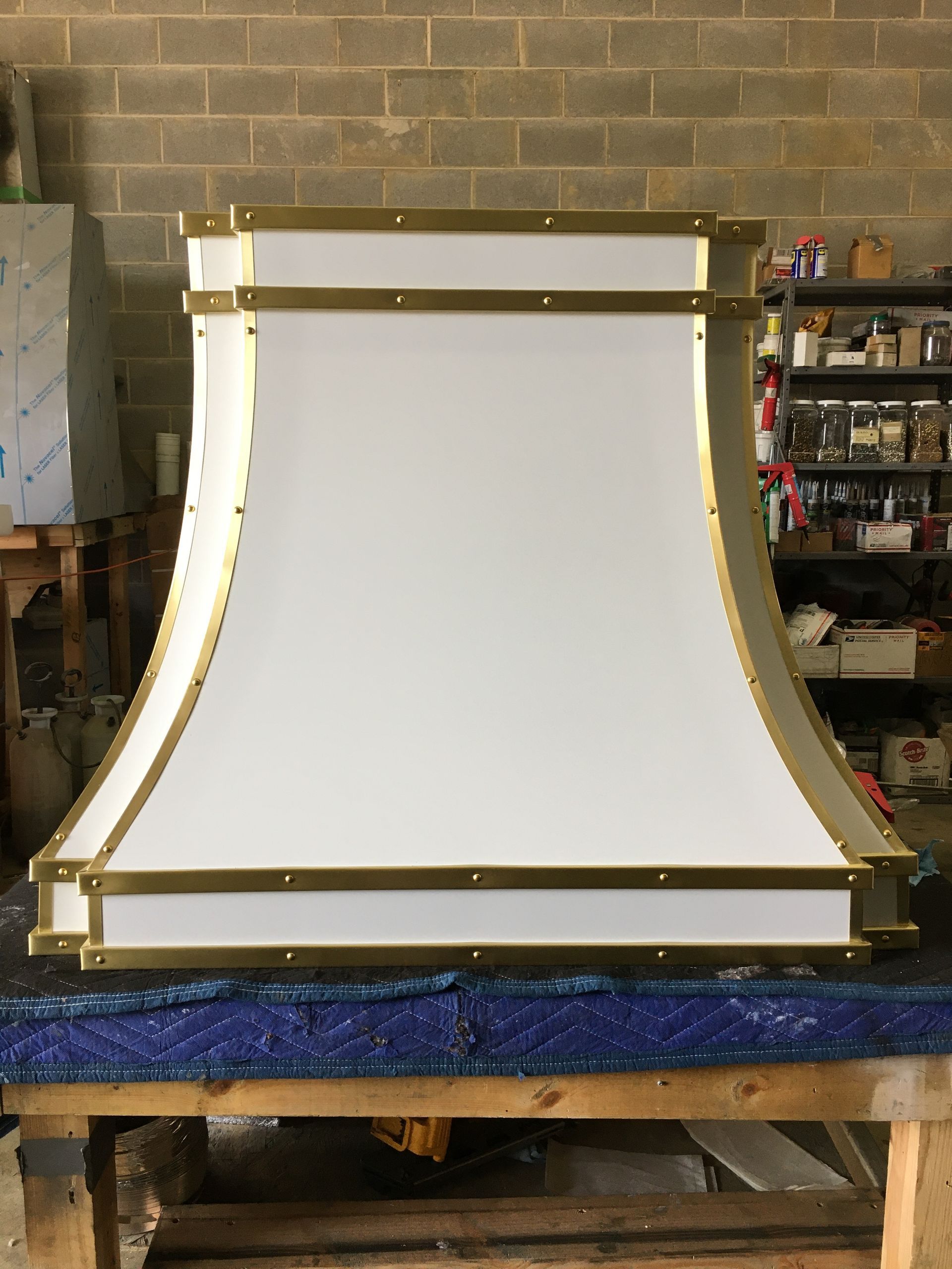 White curved panel framed in gold on a workbench in a workshop
