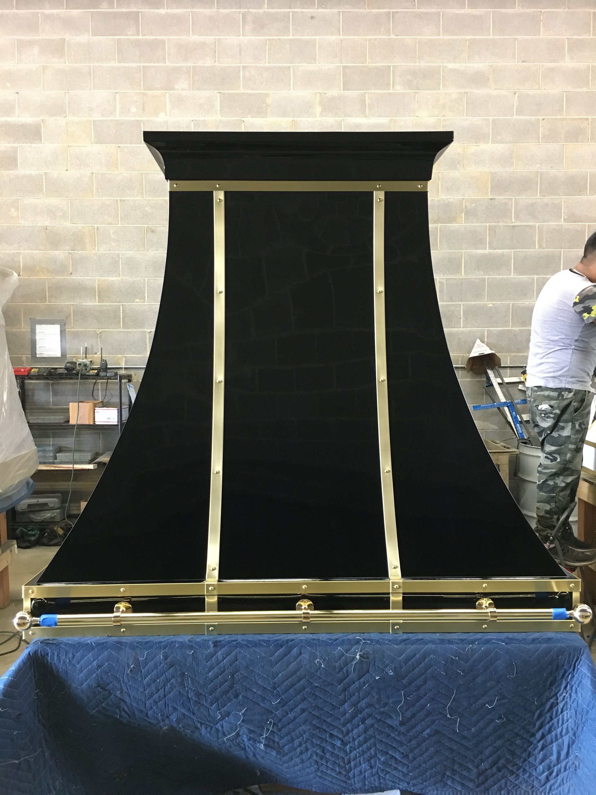 Black draped display or stage backdrop with gold trim on a table in a workshop setting