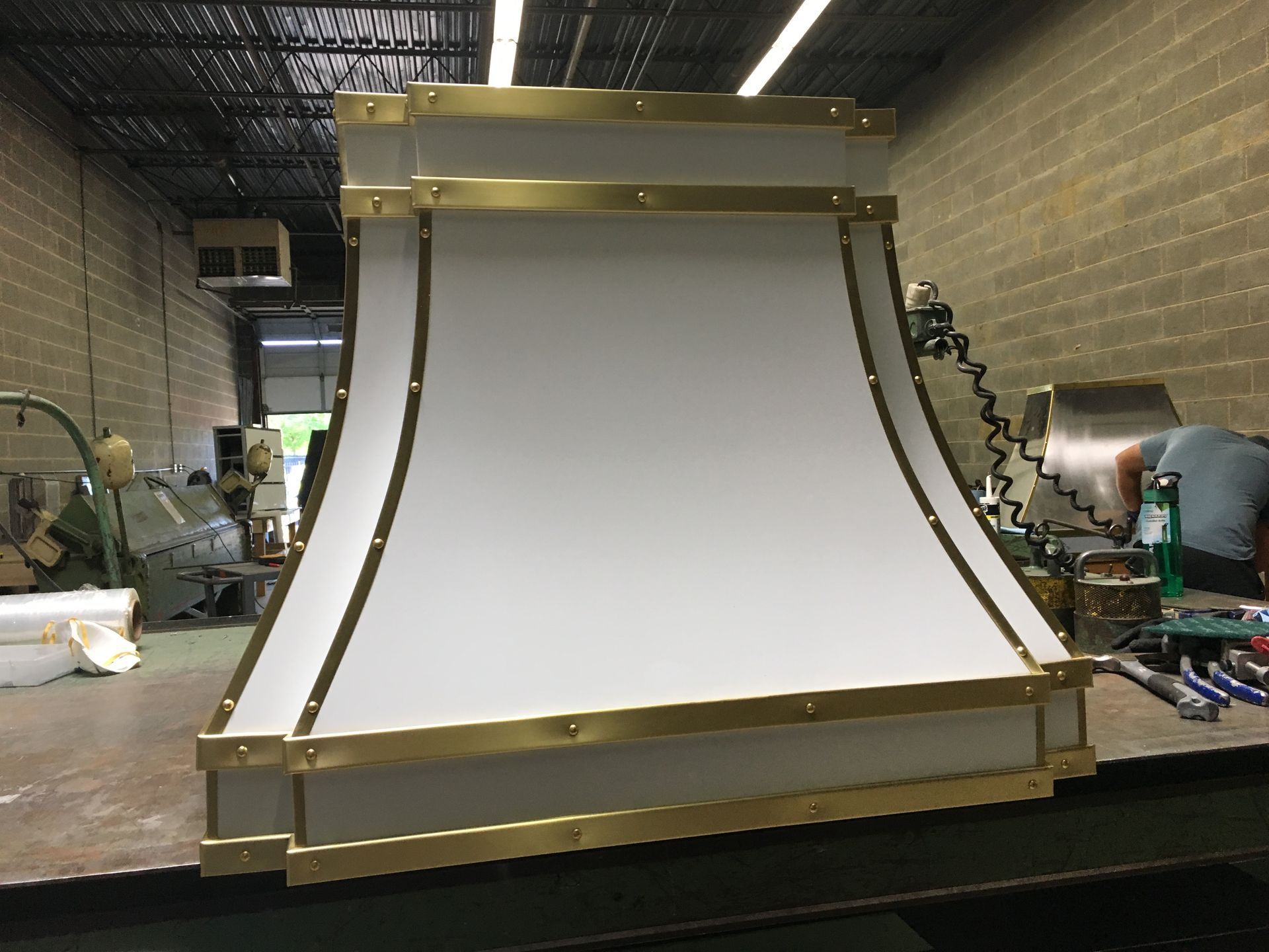 Large white curved industrial panel with gold trim in a workshop storage area