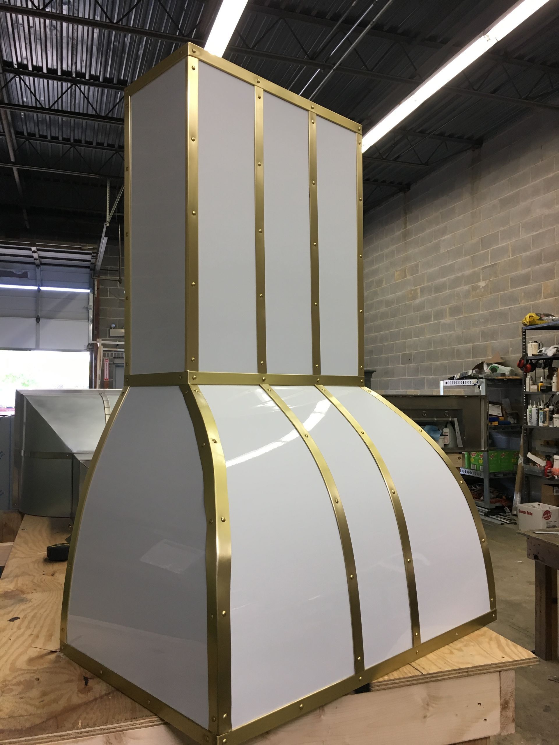 Large white and gold HVAC duct assembly in a workshop, sitting on a wooden pallet.