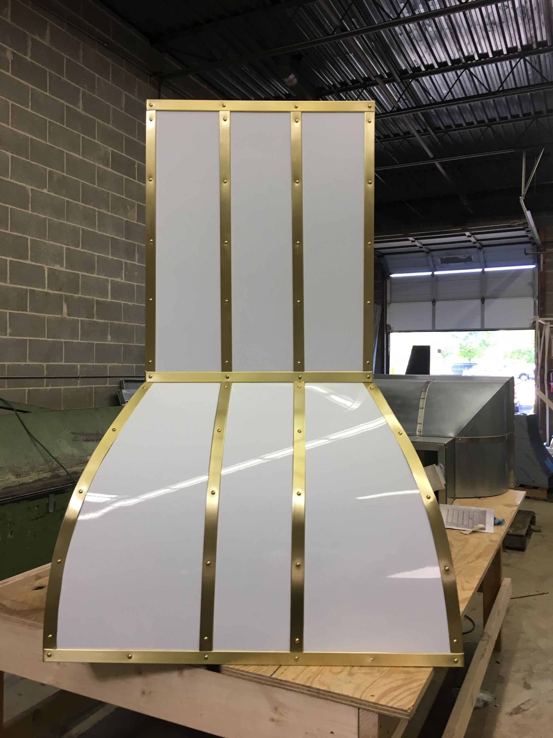 Curved white-and-gold paneled structure in a workshop or warehouse setting