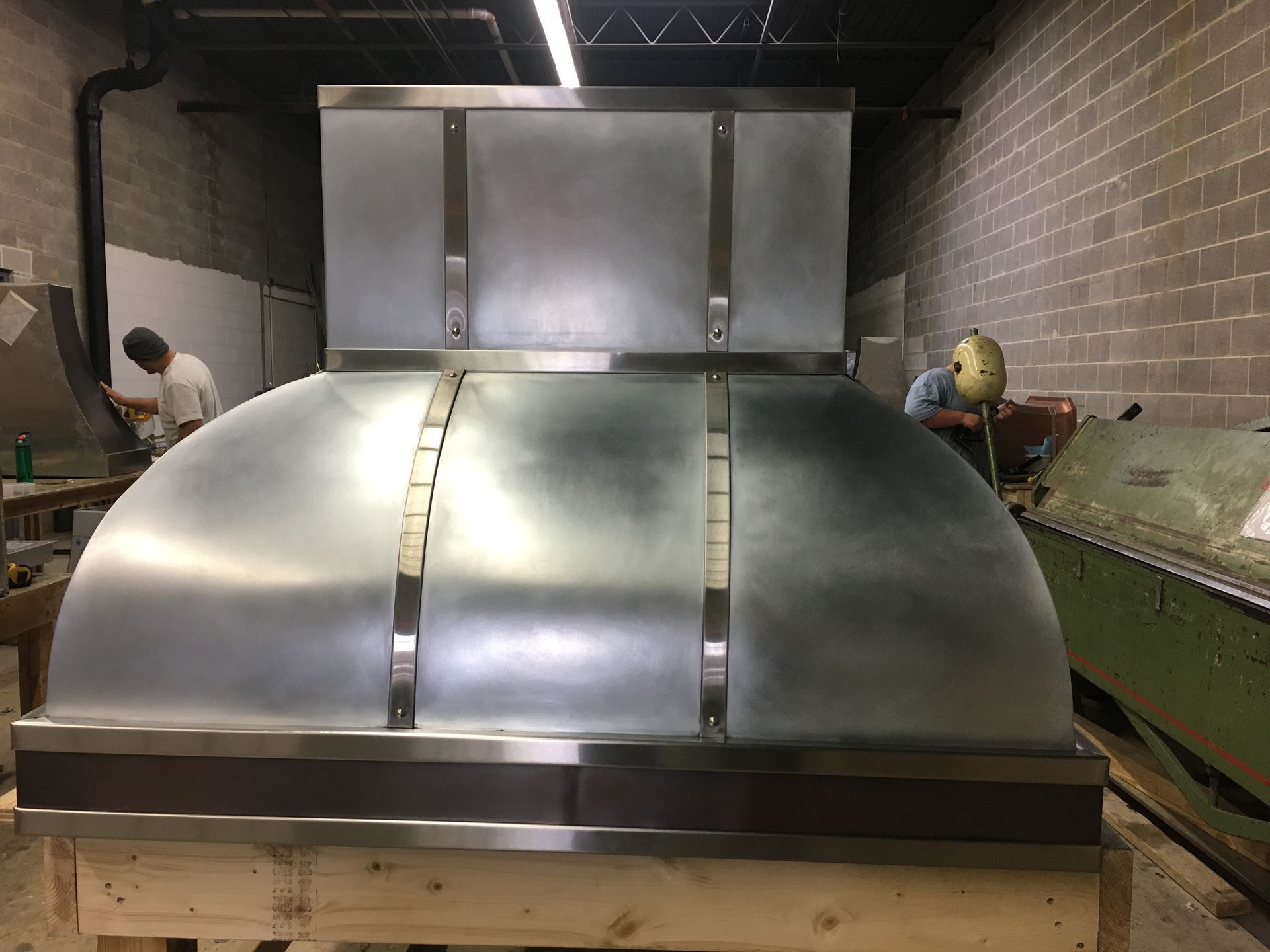 Large stainless steel industrial machine in a workshop, with a worker in the background