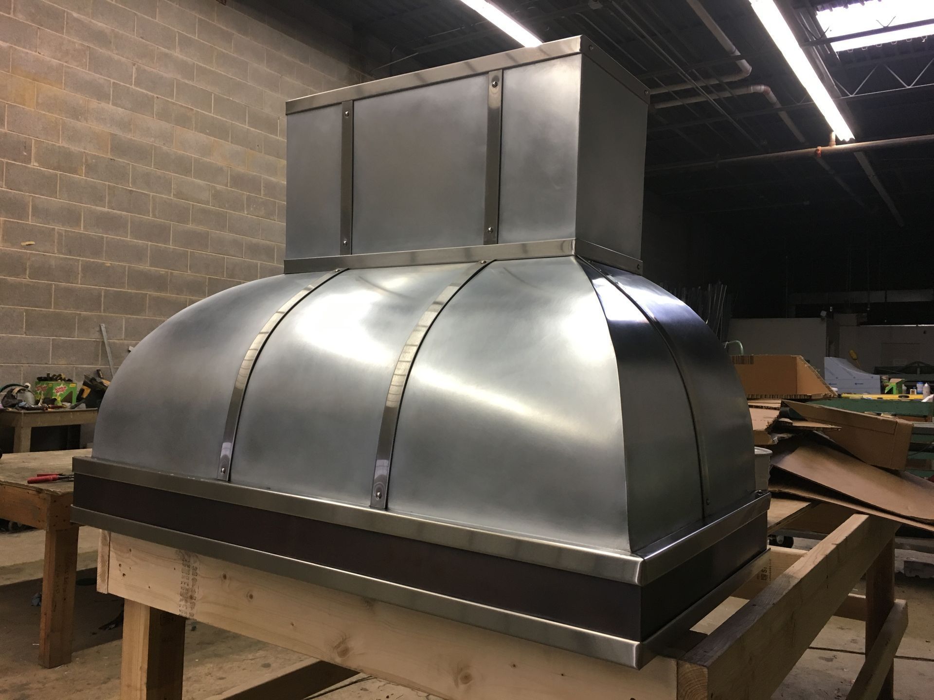Stainless steel industrial hood or duct assembly on a wooden pallet in a warehouse