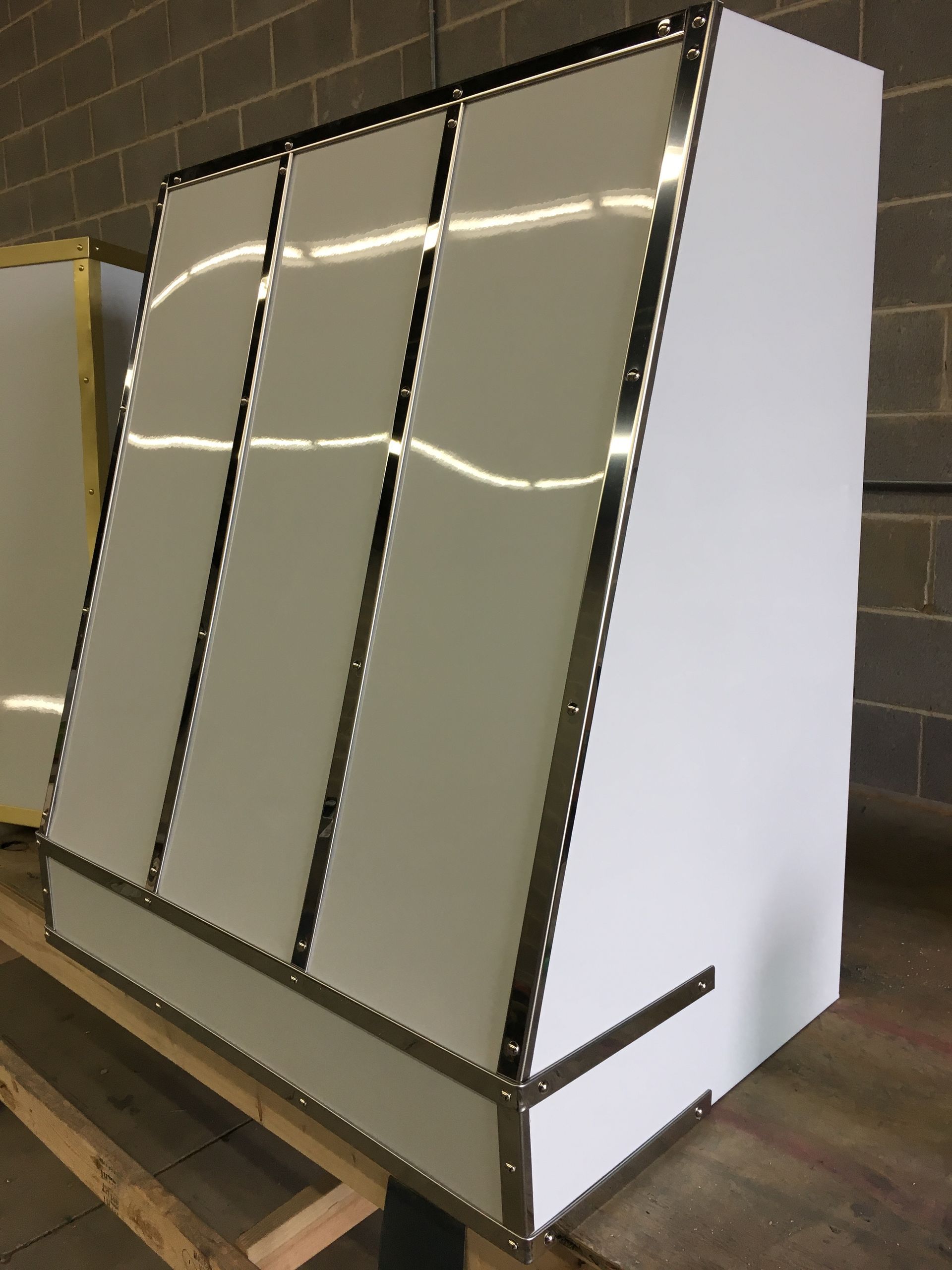 White slanted display cabinet with reflective front panels in a warehouse setting