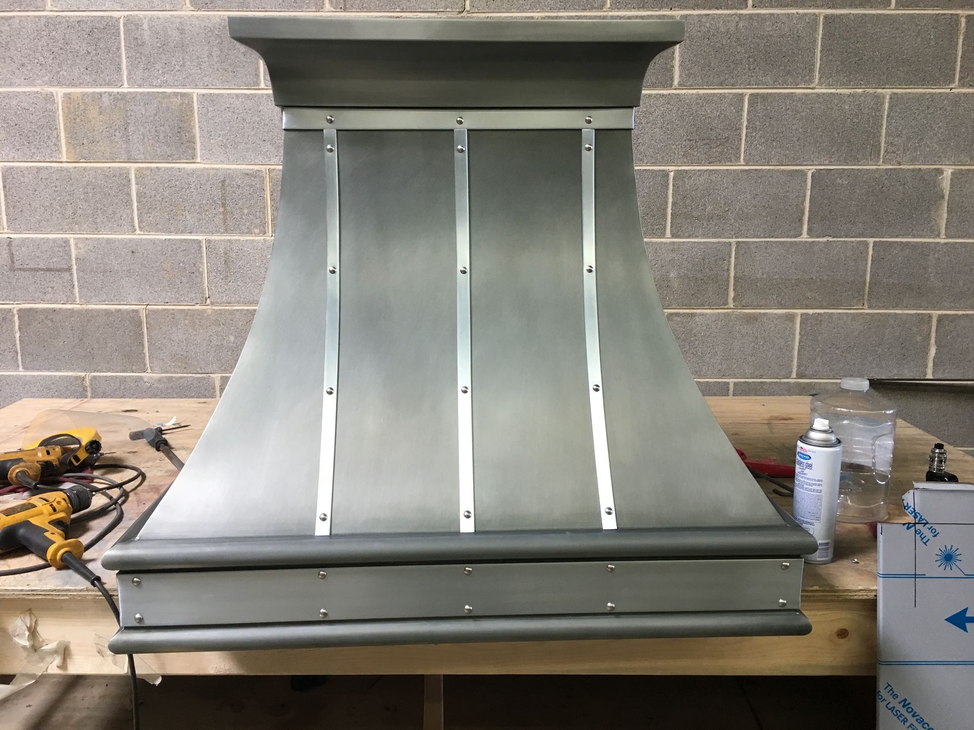 Metal chimney hood on a workbench against a cinder block wall