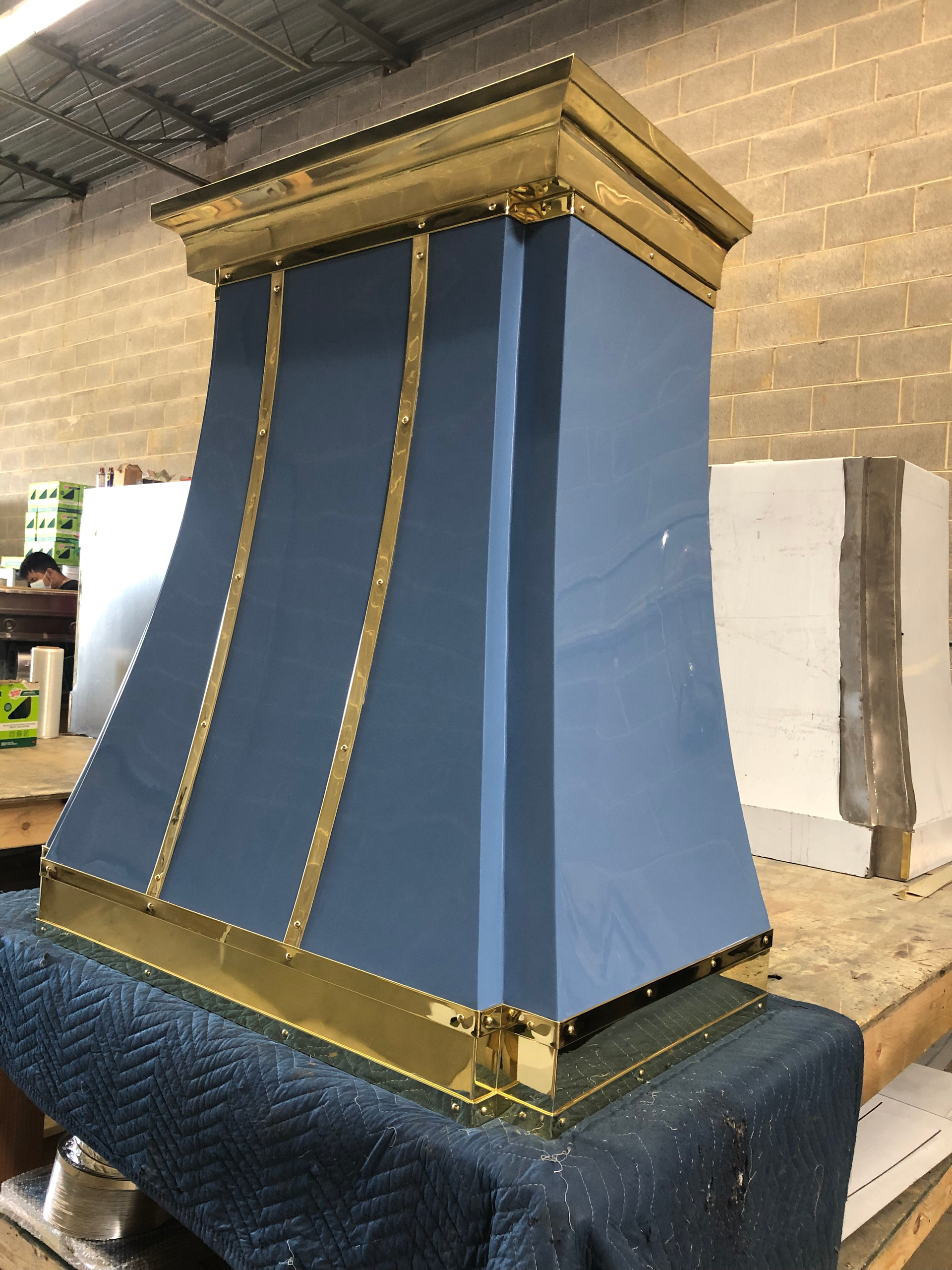 Blue and gold decorative column-shaped structure in a workshop, resting on a covered table
