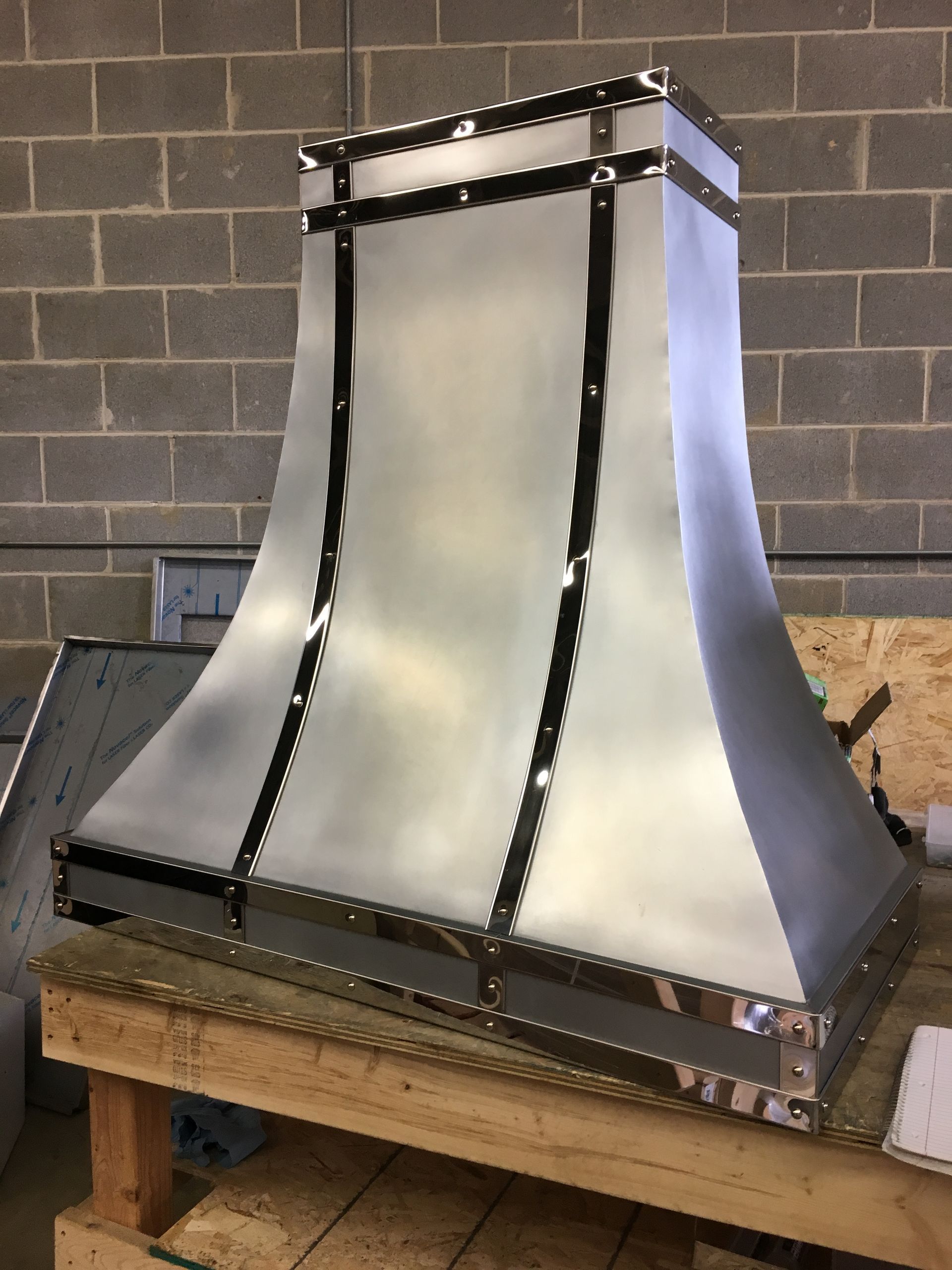 Metal sheet and black riveted frame forming a tapered hood or enclosure on a workbench
