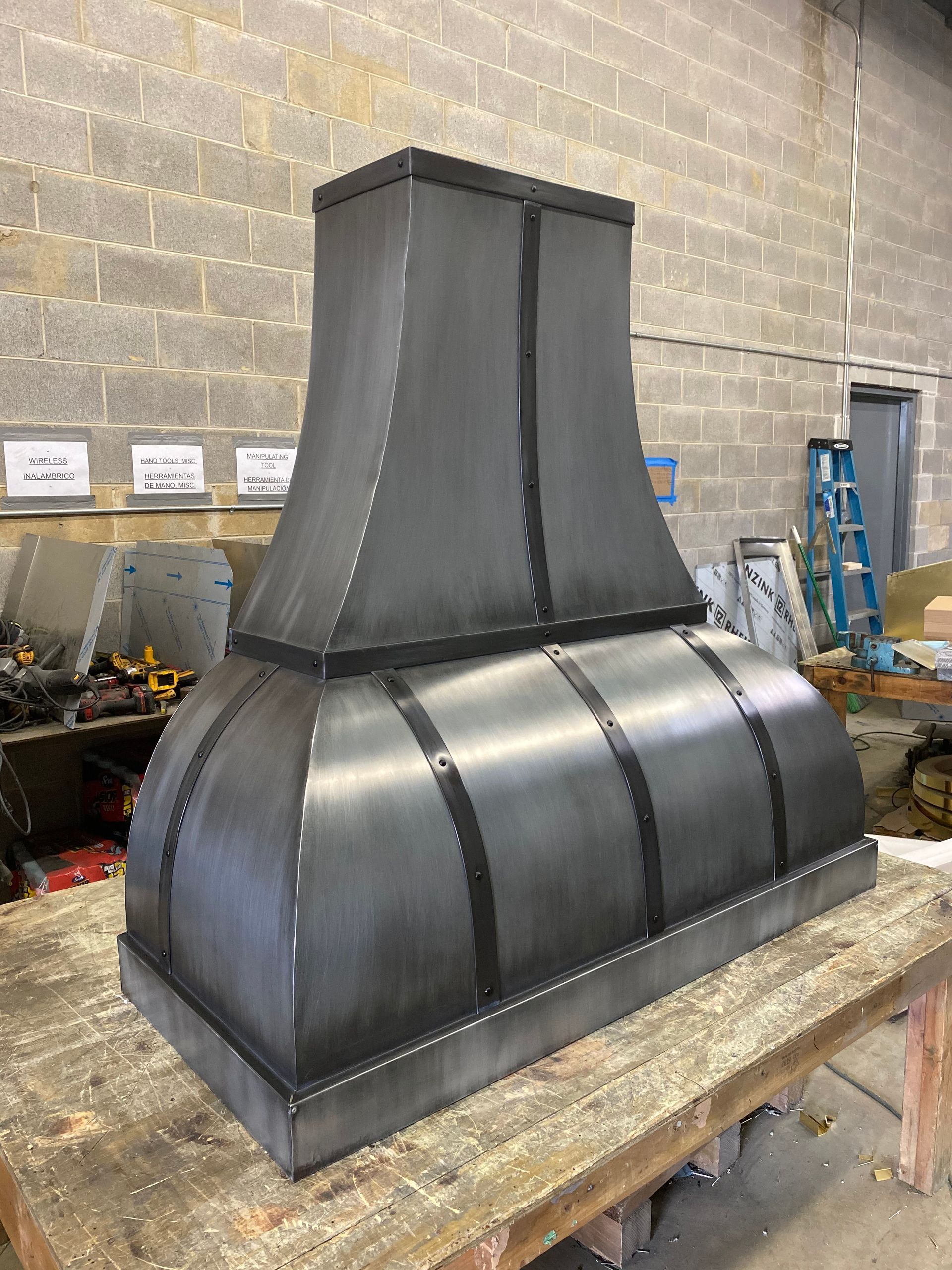 Large black metal duct hood on a workbench in an industrial workshop