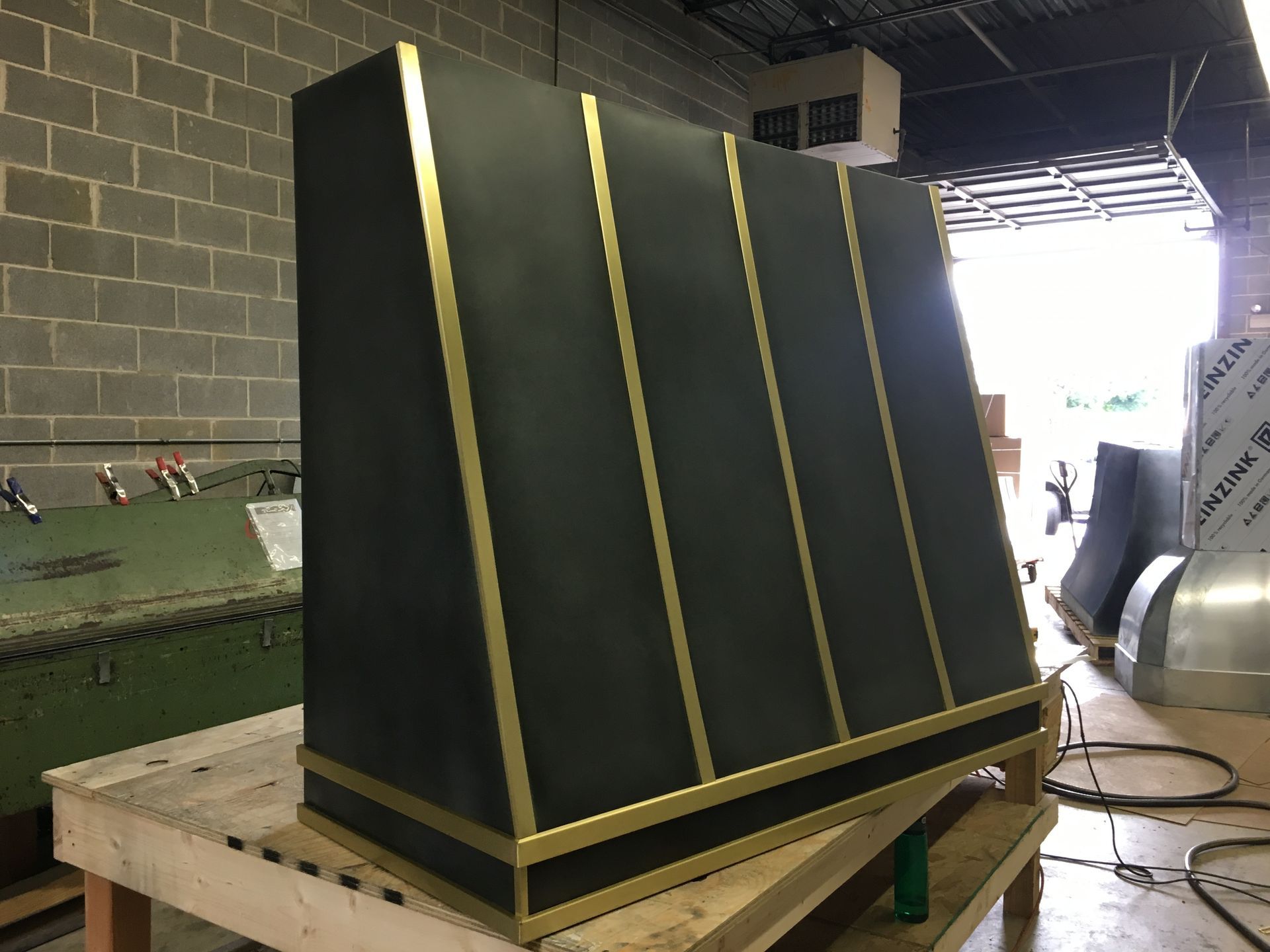 Black-and-gold industrial machine housing on a wooden pallet in a workshop