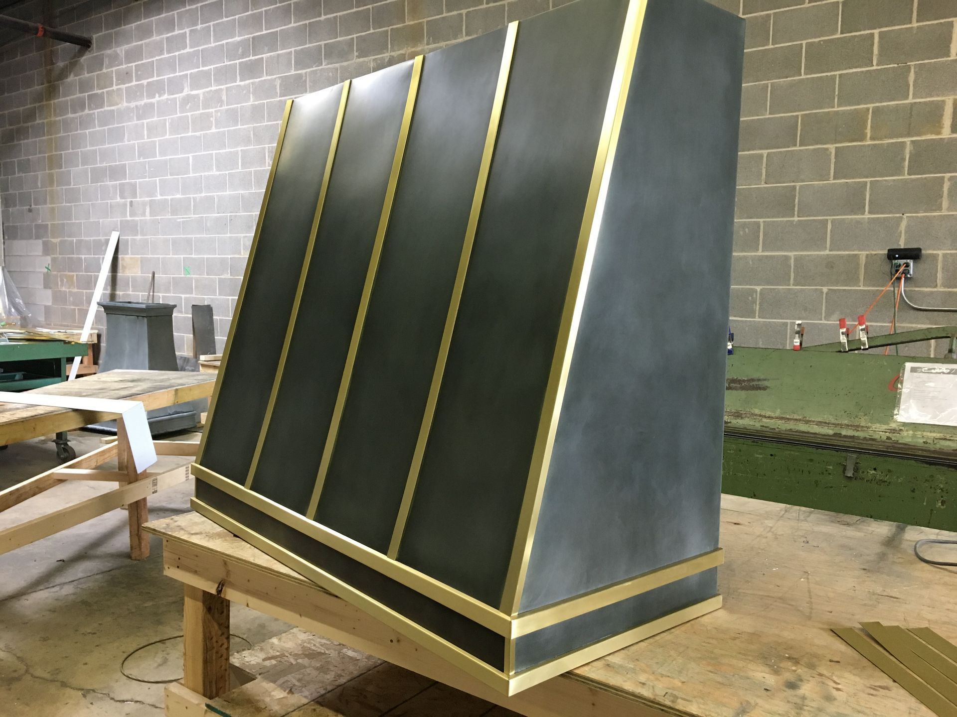 Black angled panel with gold trim on a wooden stand in a workshop.
