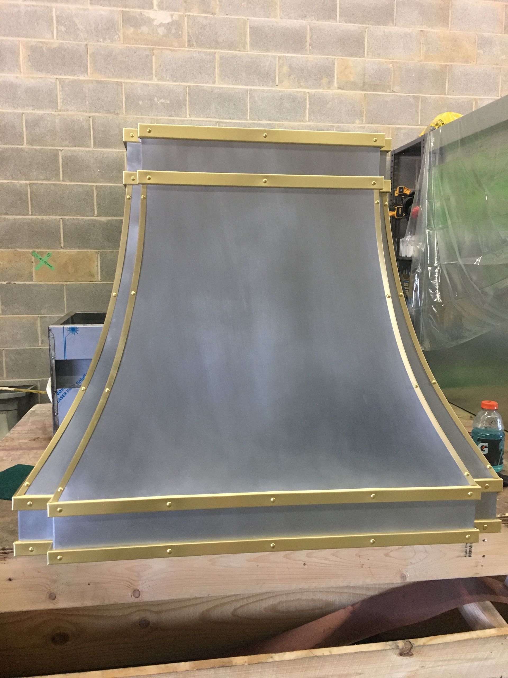 Gray curved metal ramp with yellow trim, leaning against a cinder block wall in a workshop.
