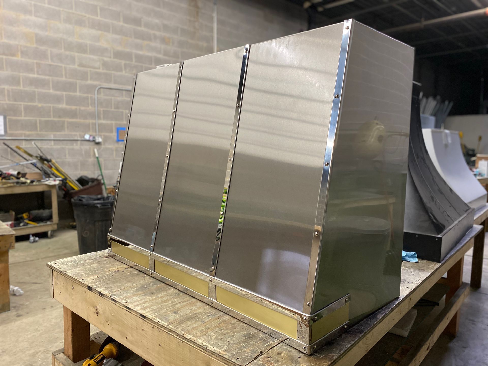 Large stainless steel duct enclosure on a workbench in an industrial workshop