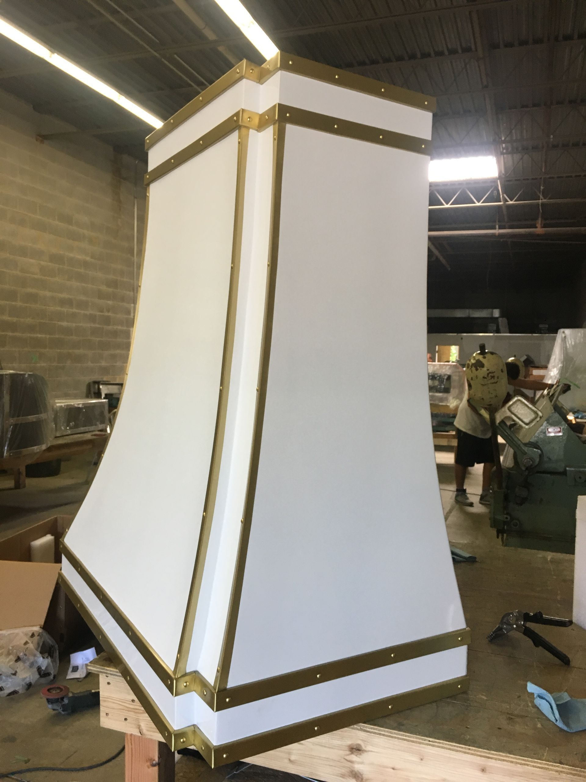 Tall white geometric structure with gold trim in a workshop warehouse area