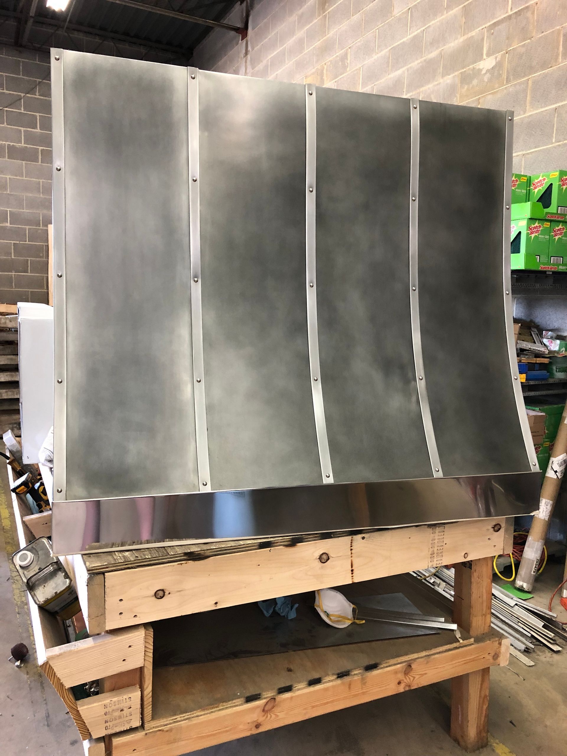 Metallic panel leaning on a wooden workbench in a workshop or garage setting