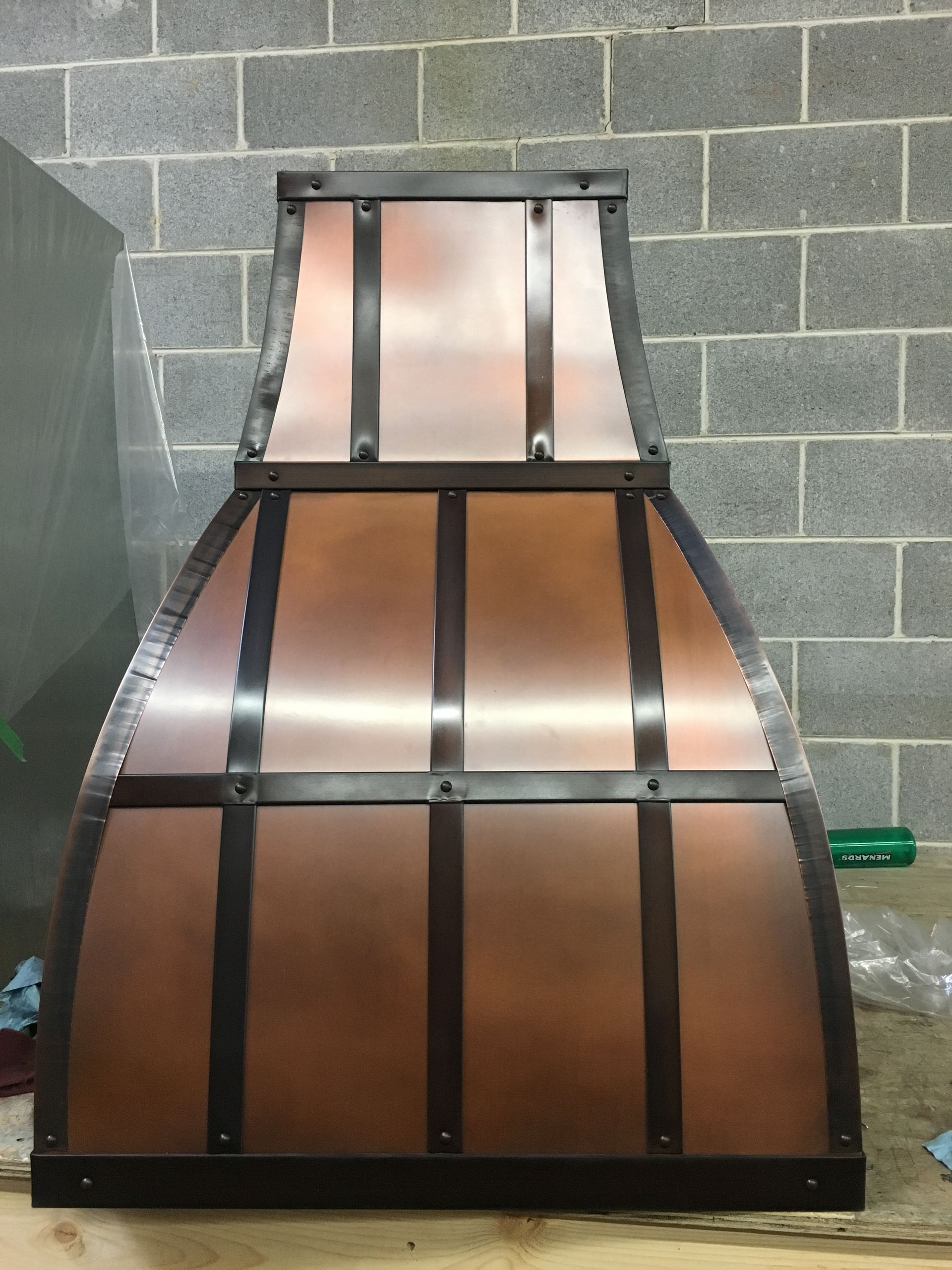 Black-framed copper chimney hood against a gray cinderblock wall