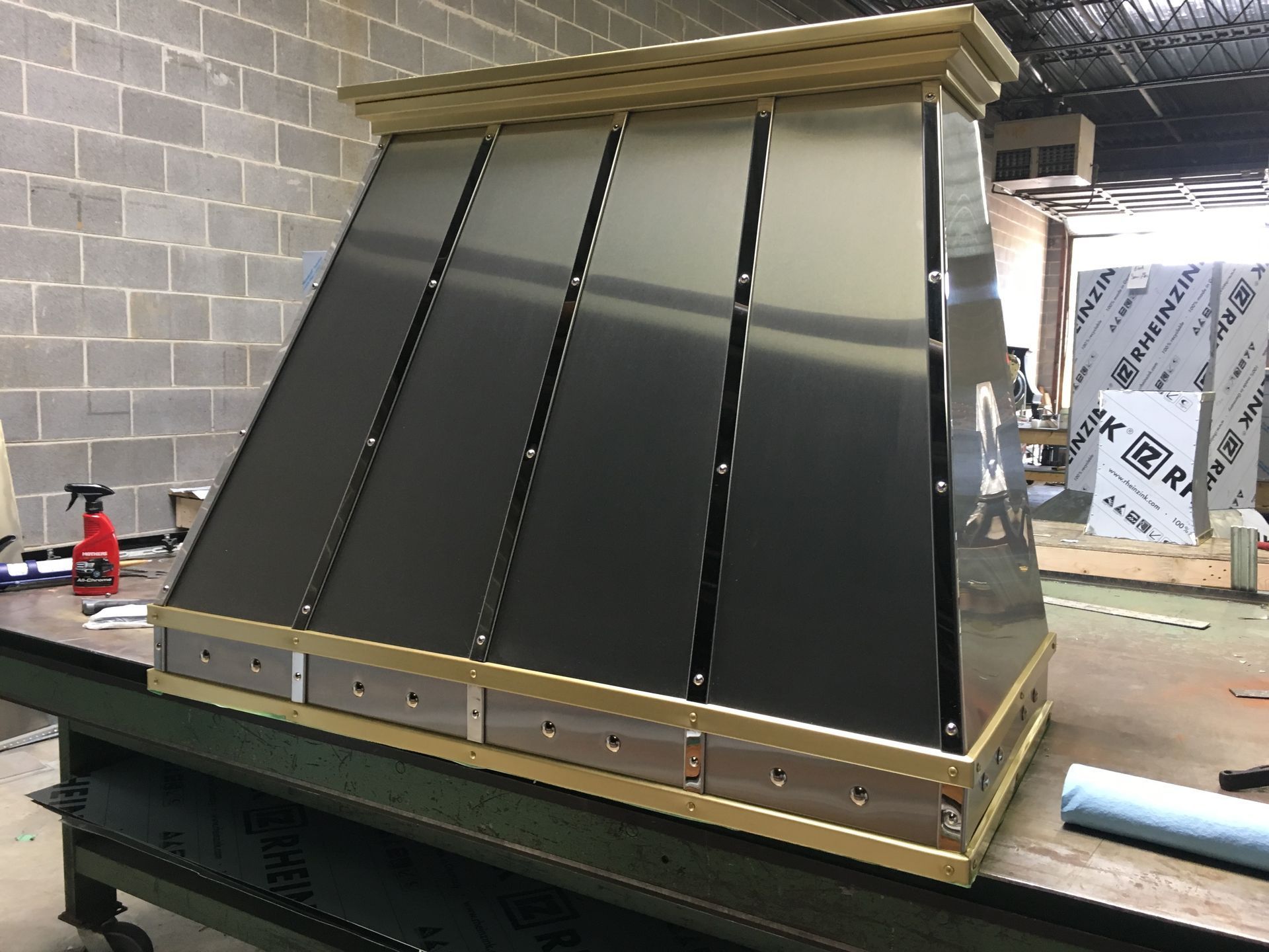 Large black metal machine housing with gold trim in an industrial workshop