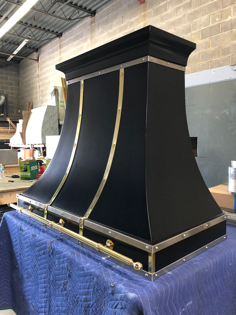 Large black decorative architectural model with gold trim on a blue-covered table in a workshop