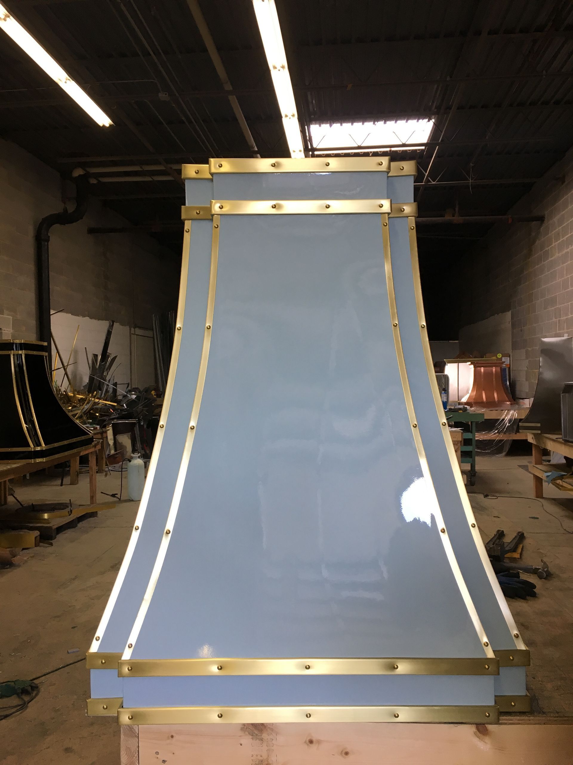 Large blue curved panel with gold trim standing in a workshop or warehouse.