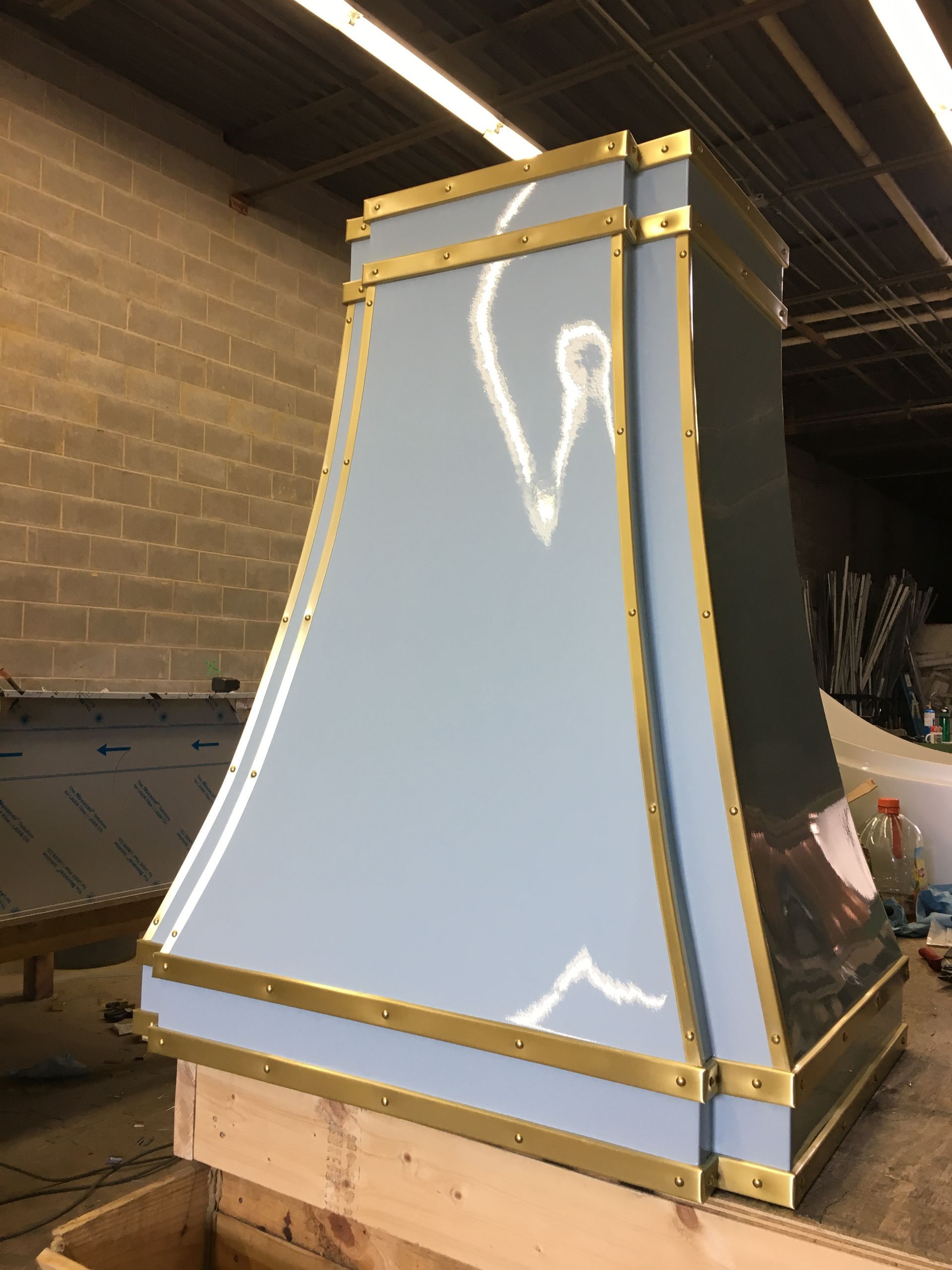 Large blue-and-gold tapered display structure on a pallet in an indoor workshop