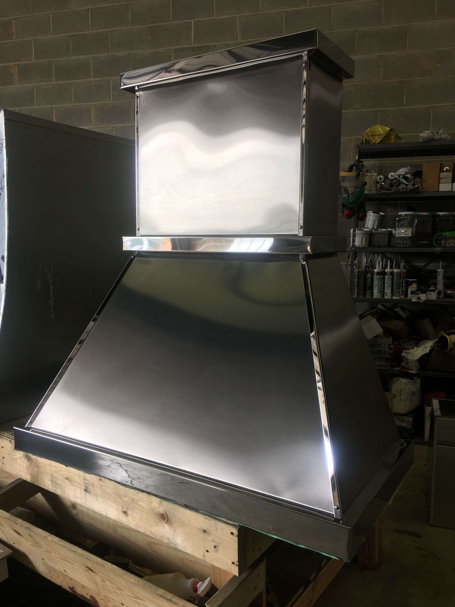 Metal ventilation hood with shiny stainless-steel ducting in a workshop or garage setting
