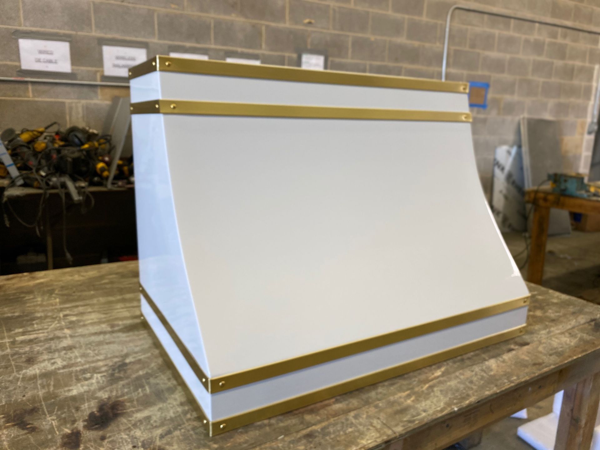 White and gold rectangular display box on a wooden workbench in a workshop