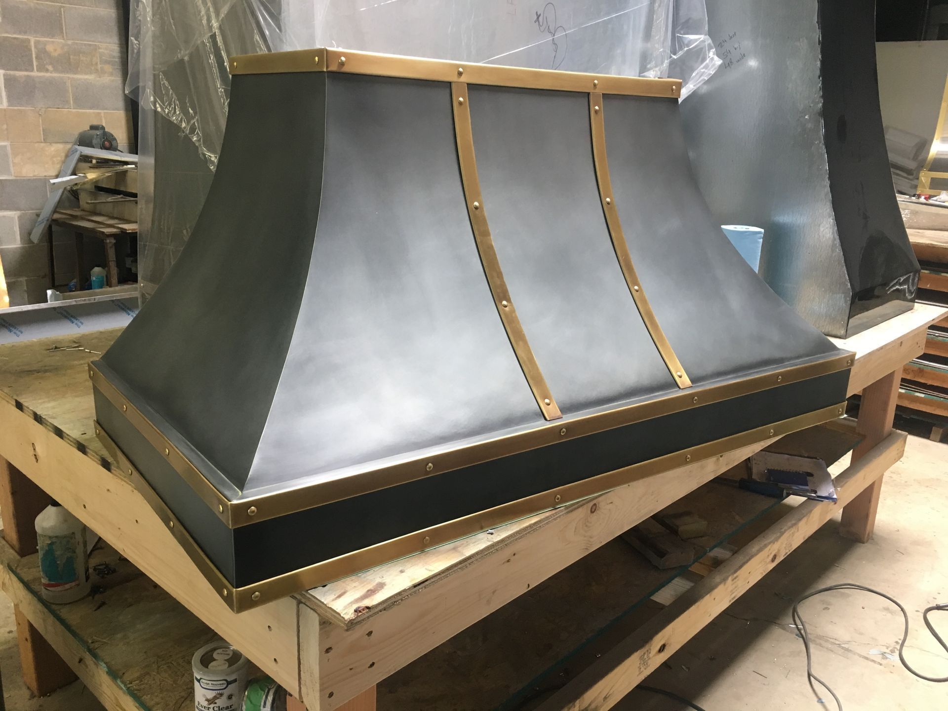 Gray metal roof vent hood on a wooden pallet in a workshop, with unfinished seams and a top cap.