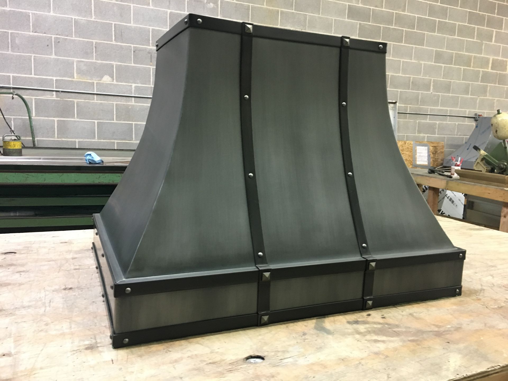 Black metal ventilation hood on a workbench in an industrial workshop