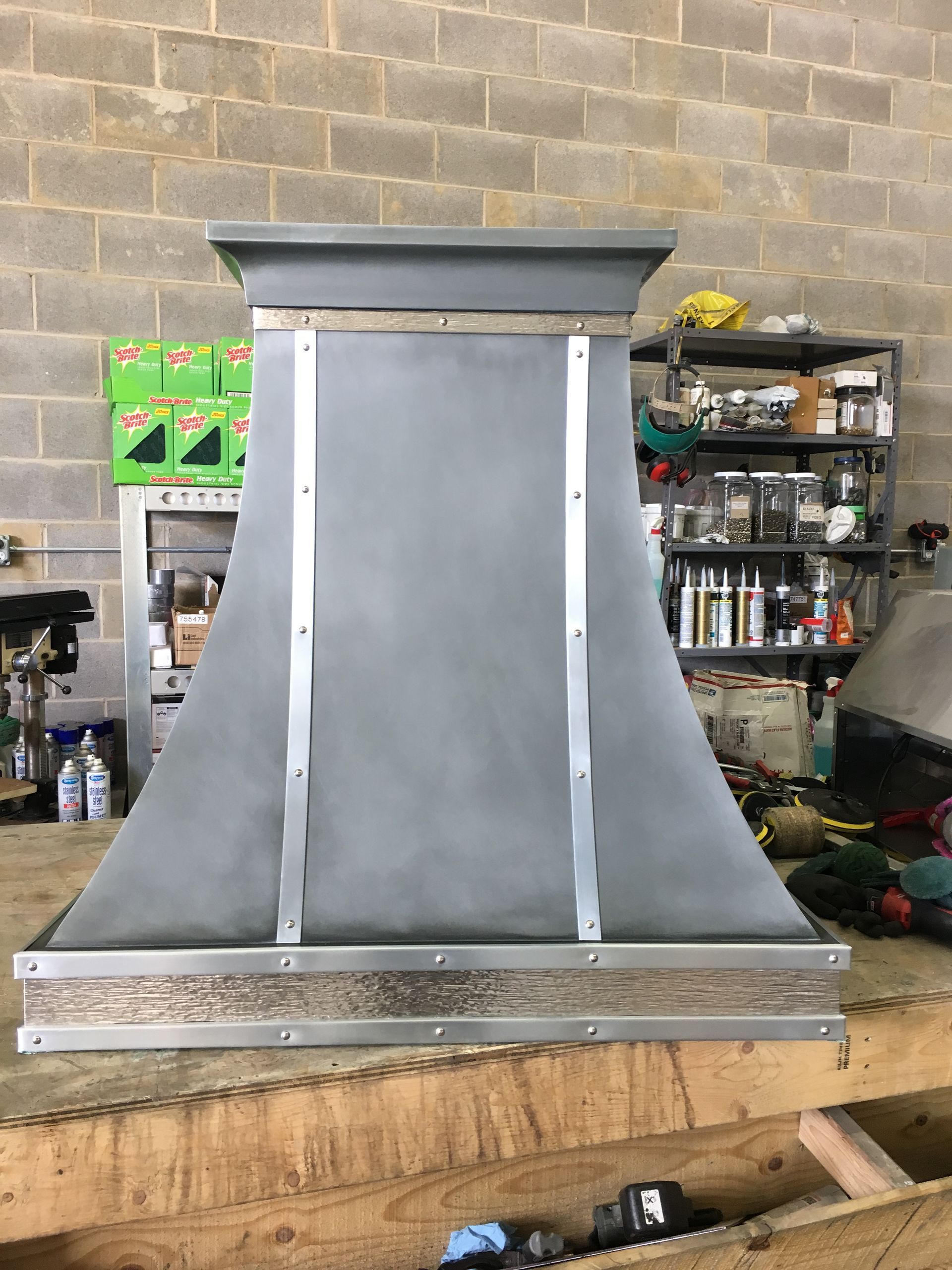 Large gray metal hood or vent assembly on a workbench in a workshop