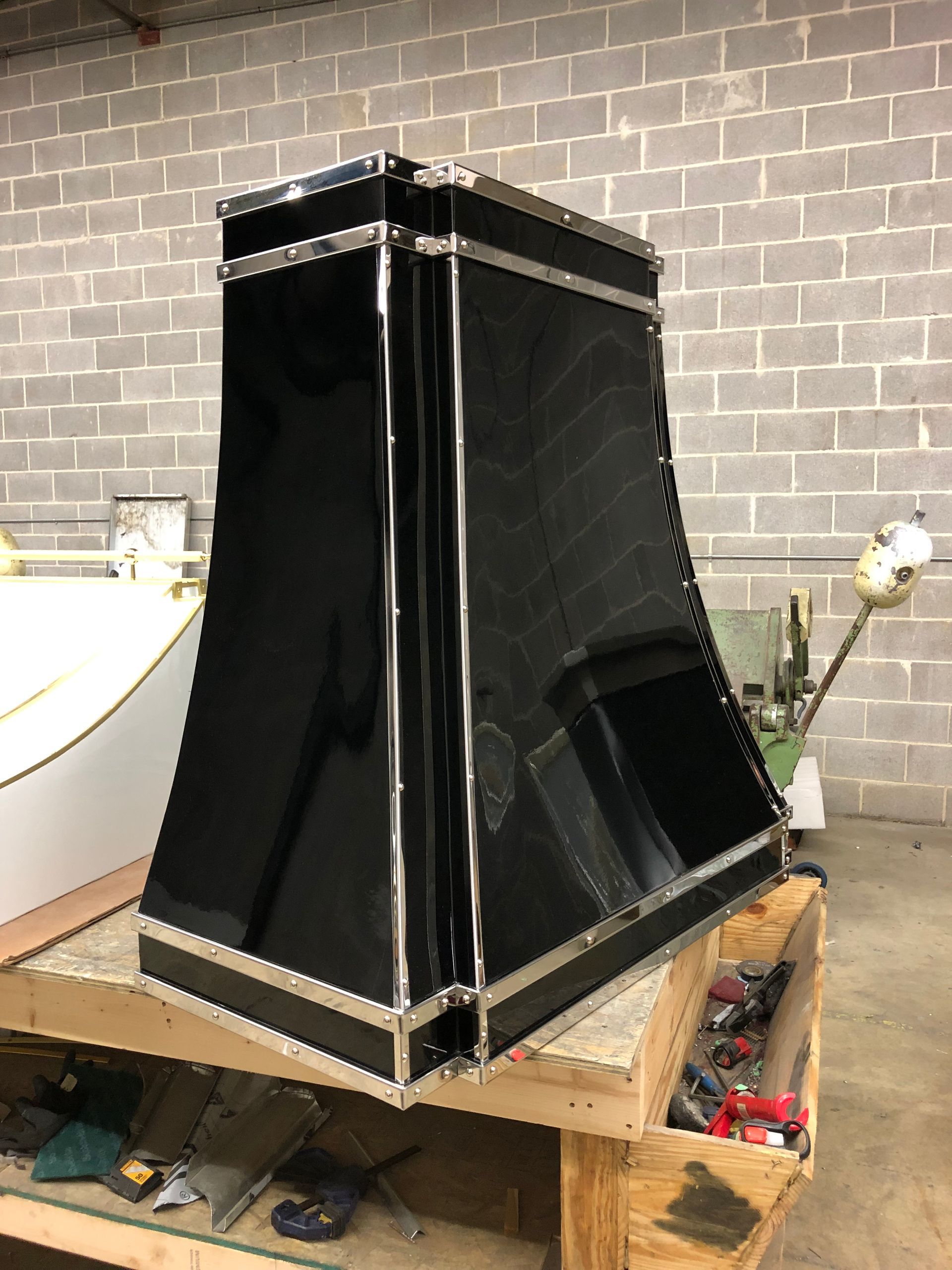 Black rectangular decorative enclosure with silver trim on a wooden workbench in a workshop.
