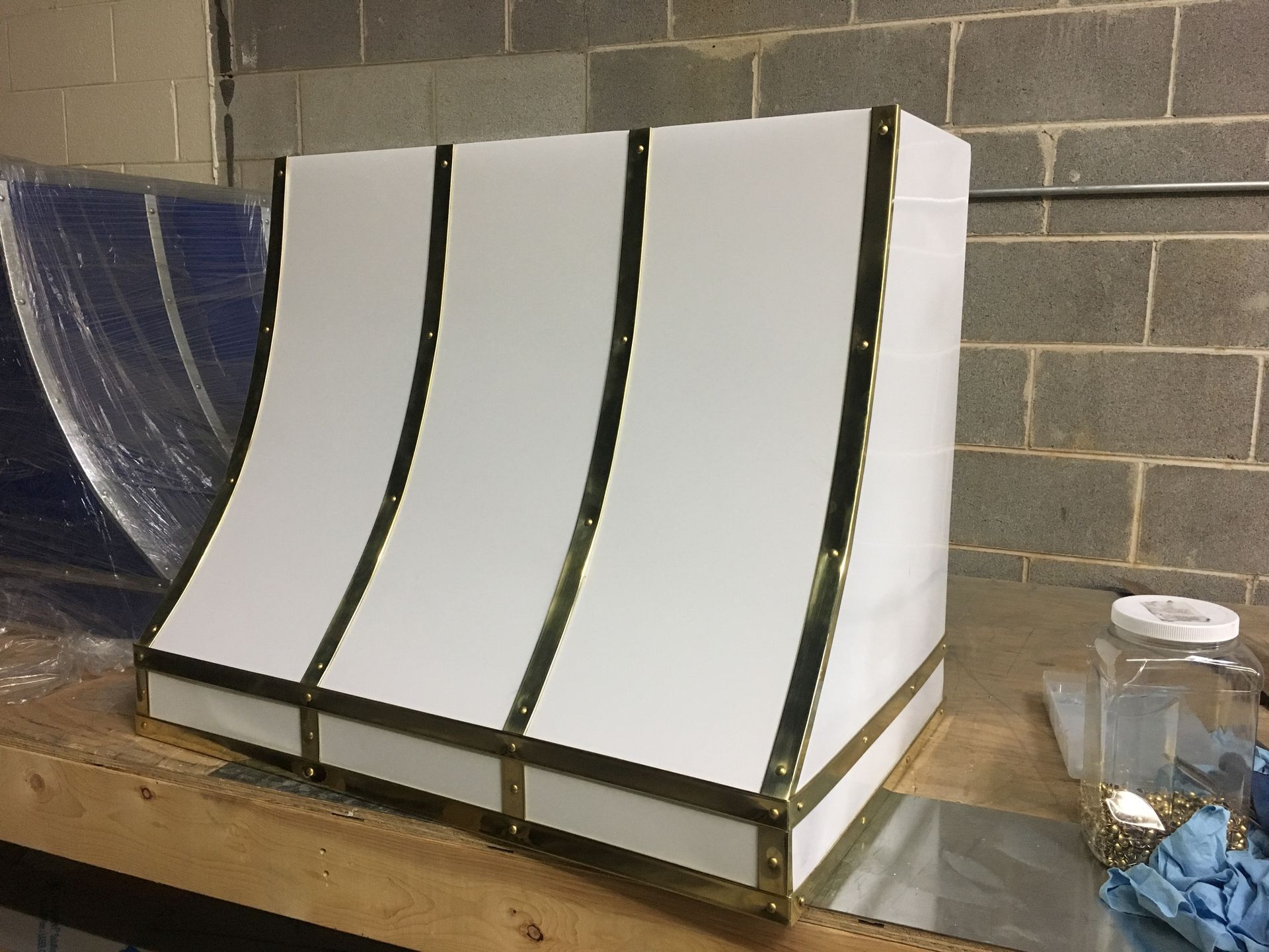 Four white curved panels on a workbench in a workshop against a cinderblock wall