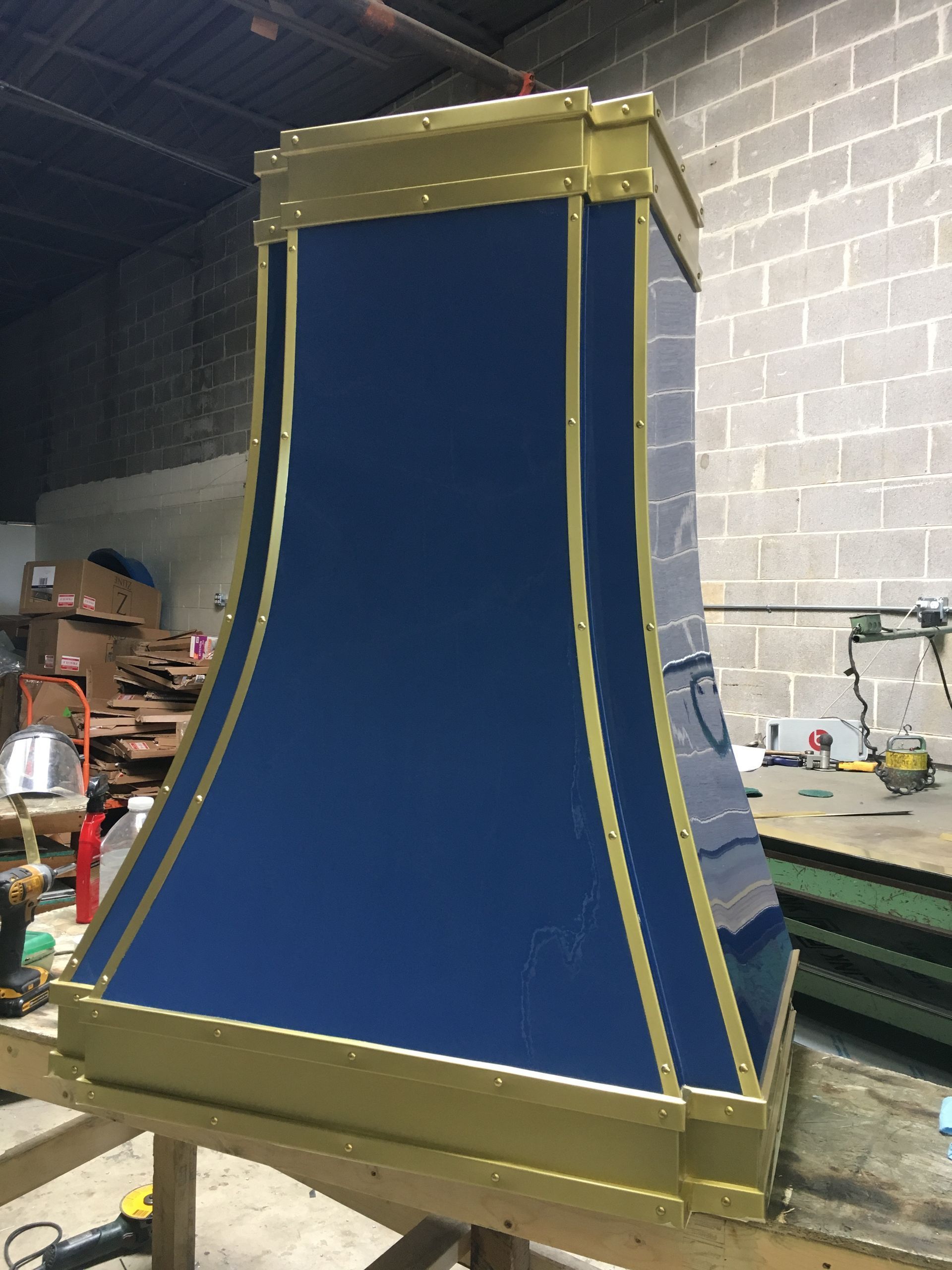 Blue fabric-covered industrial frame in a warehouse workshop, with gold metal edges and rails