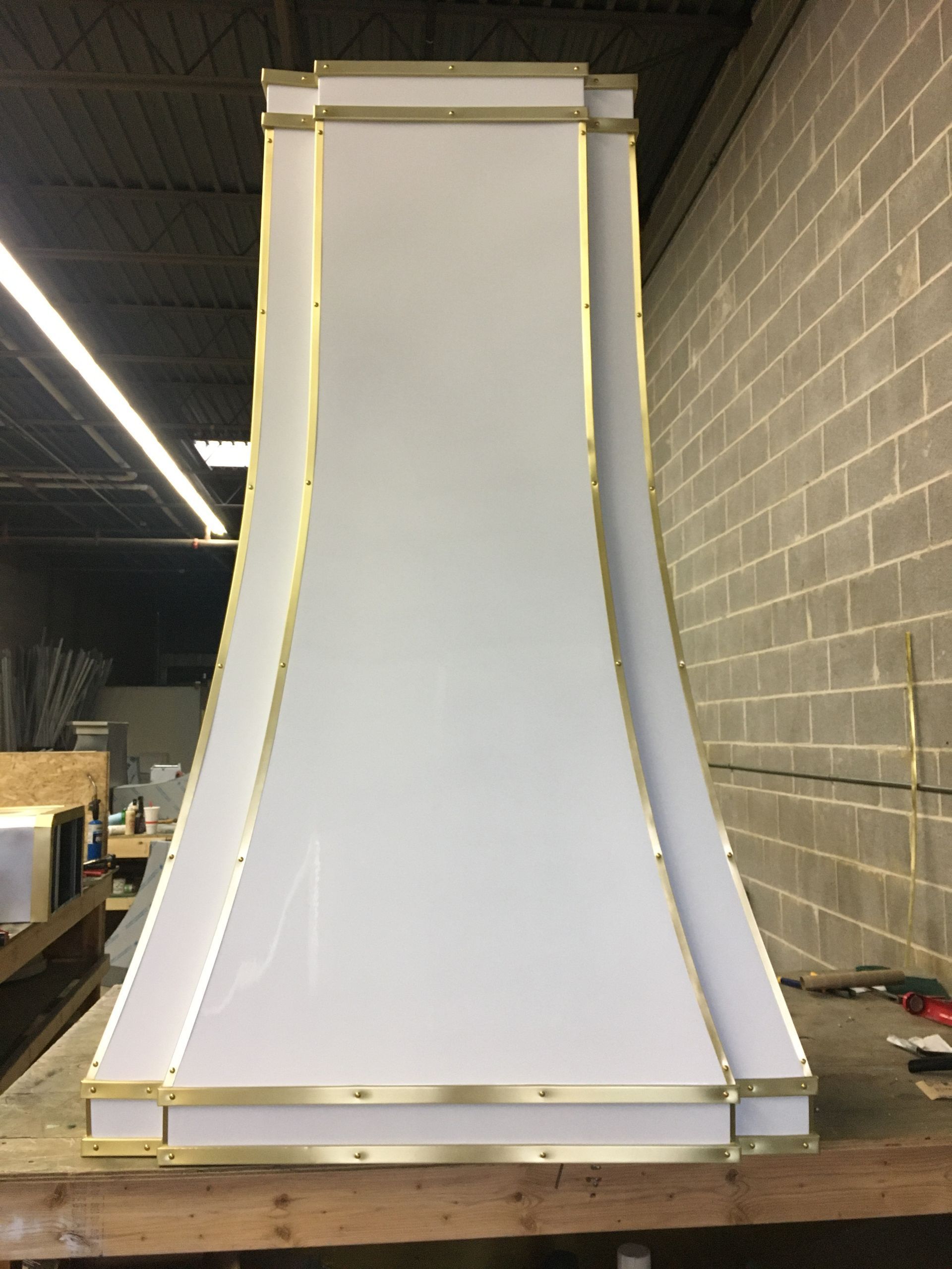 Large white curved panel with gold trim standing in a workshop or warehouse.